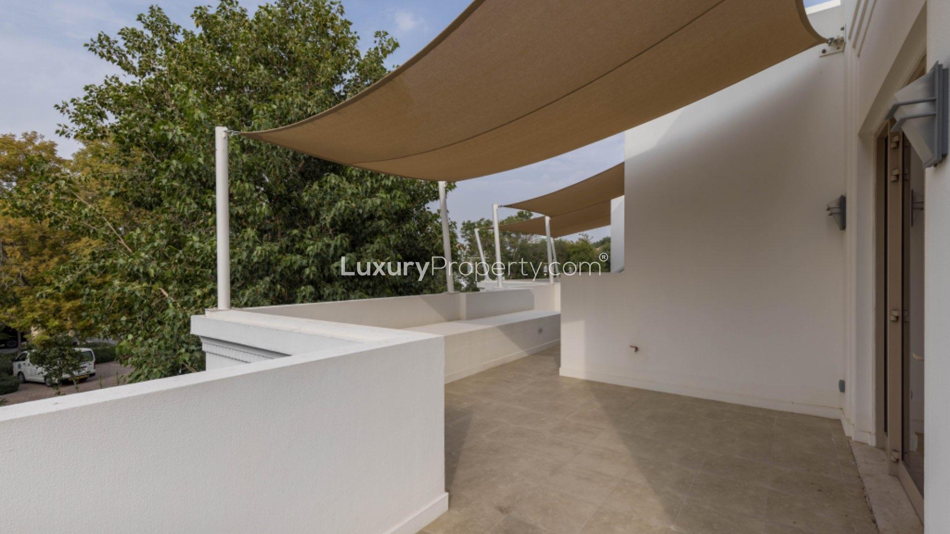 "Spacious terrace with shade in Al Barari villa, surrounded by lush greenery.",Interior view of spacious villa room with balcony, Al Barari Villas, surrounded by greenery