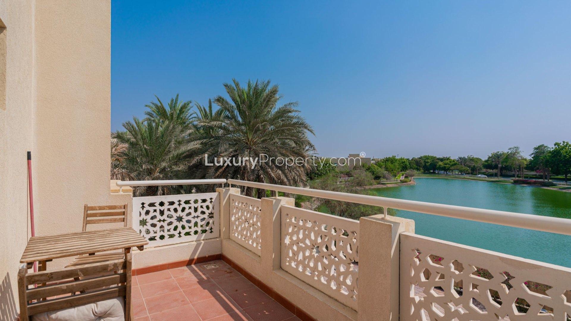 "Spacious villa exterior with patio in Meadows 2, lake-facing, for sale, 5 bedrooms.","Balcony view of lake and palm trees at spacious villa in Meadows 2, for sale.",Living room in spacious 5-bedroom villa for sale, Meadows 2, featuring elegant decor
