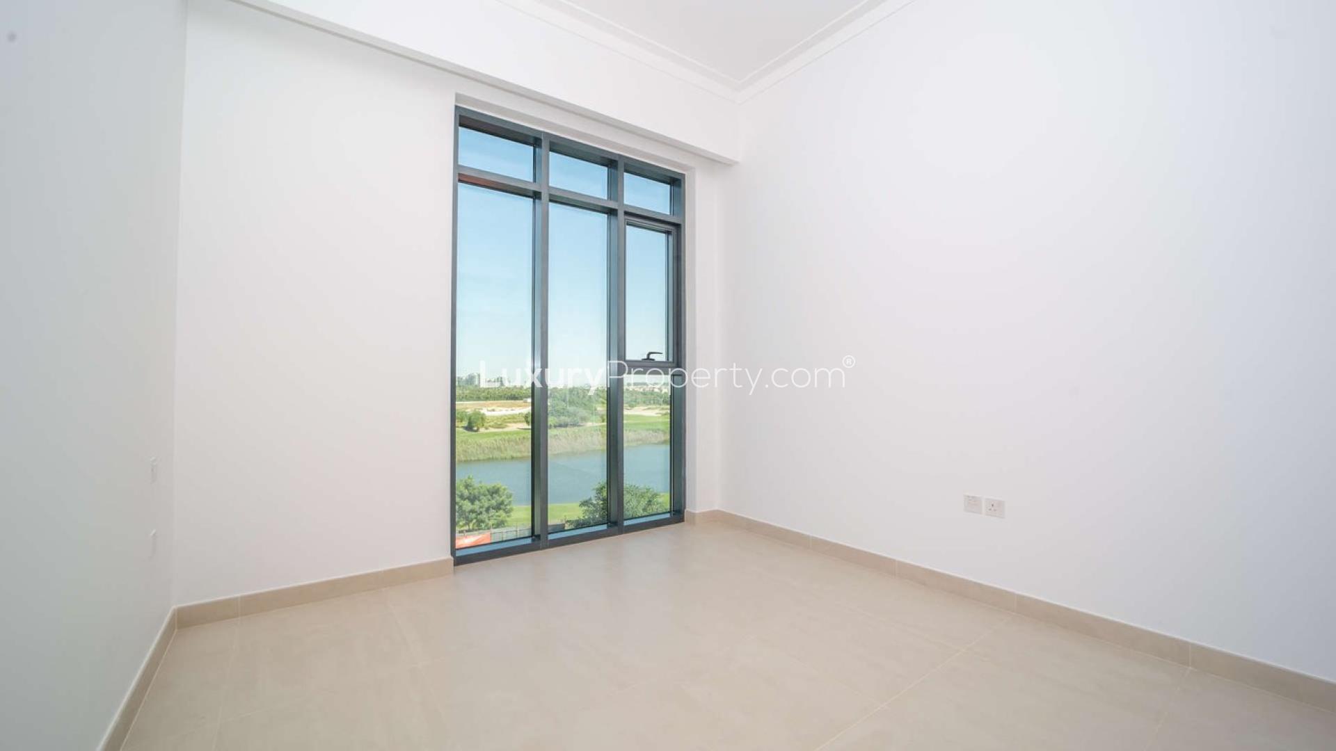 Empty room with large window overlooking scenic golf course at The Hills A apartment