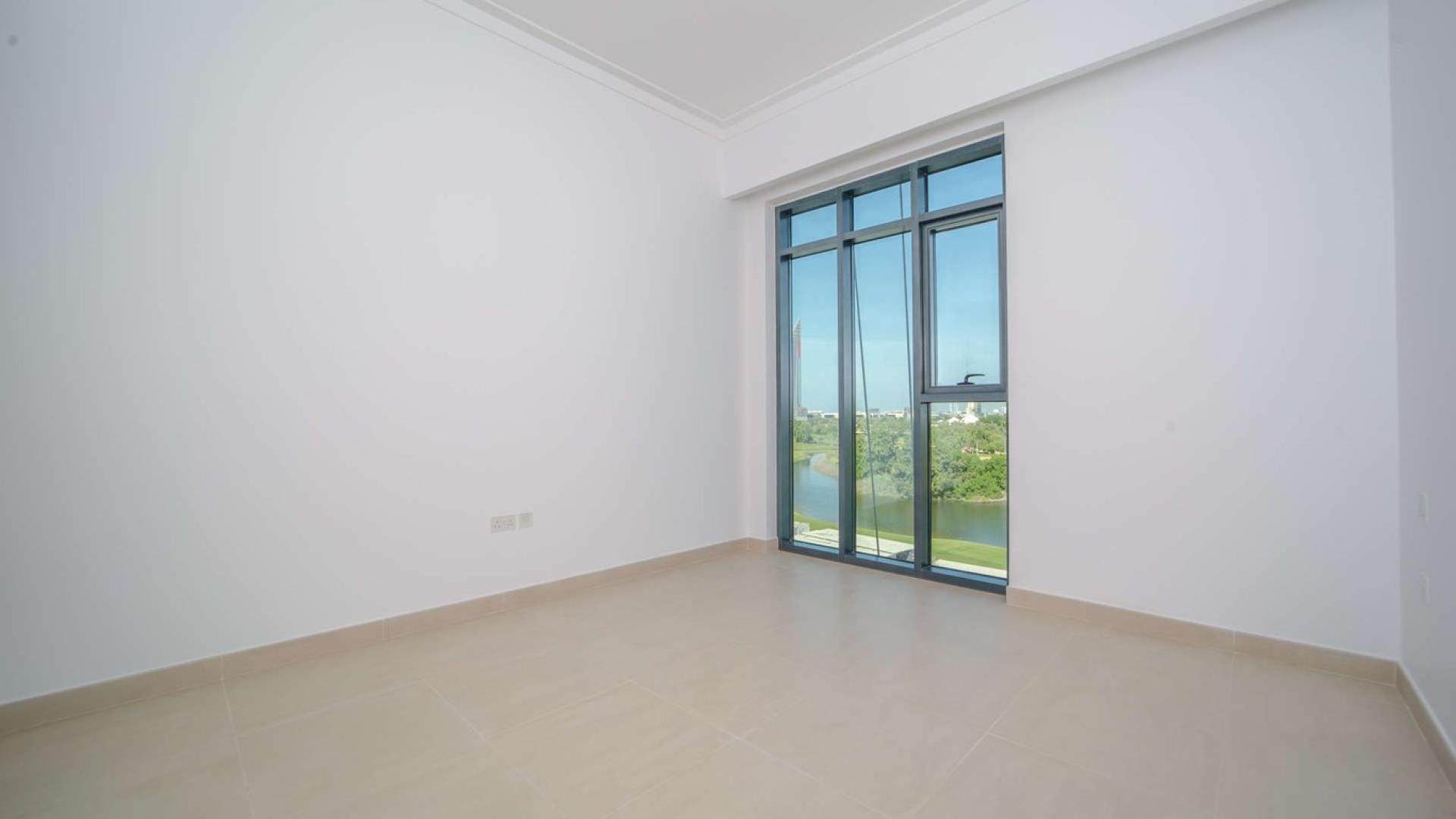 "Modern apartment building exterior with pool at The Hills A, Emirates Golf Course view.",Empty room with large window overlooking greenery in The Hills A apartment for sale
