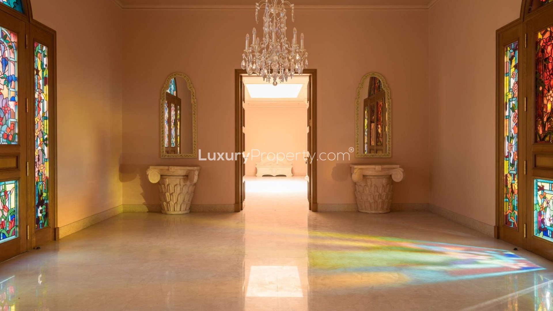 Luxurious villa hallway with elegant chandelier and vibrant stained glass doors in Umm Suqeim