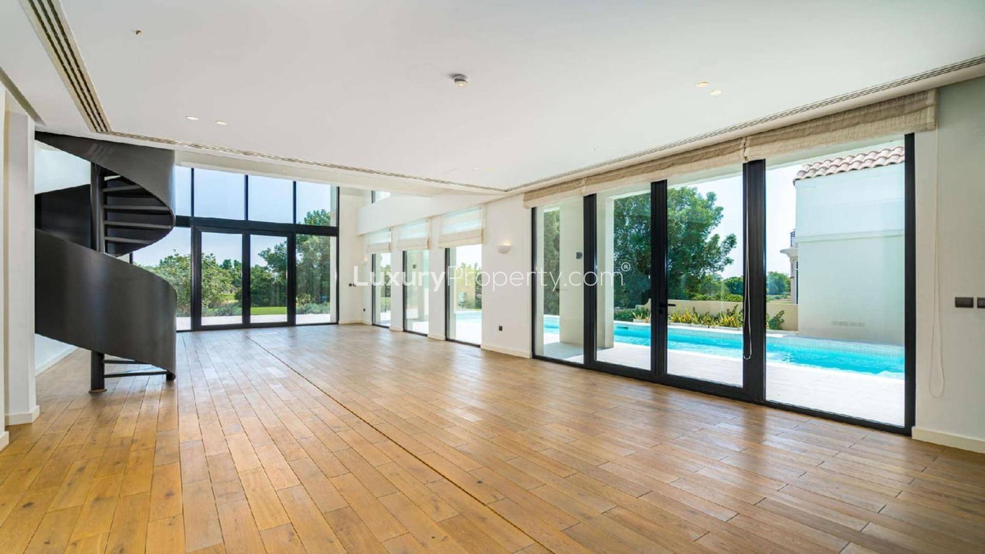 Spacious villa interior with spiral staircase and pool view in Jumeirah Golf Estates