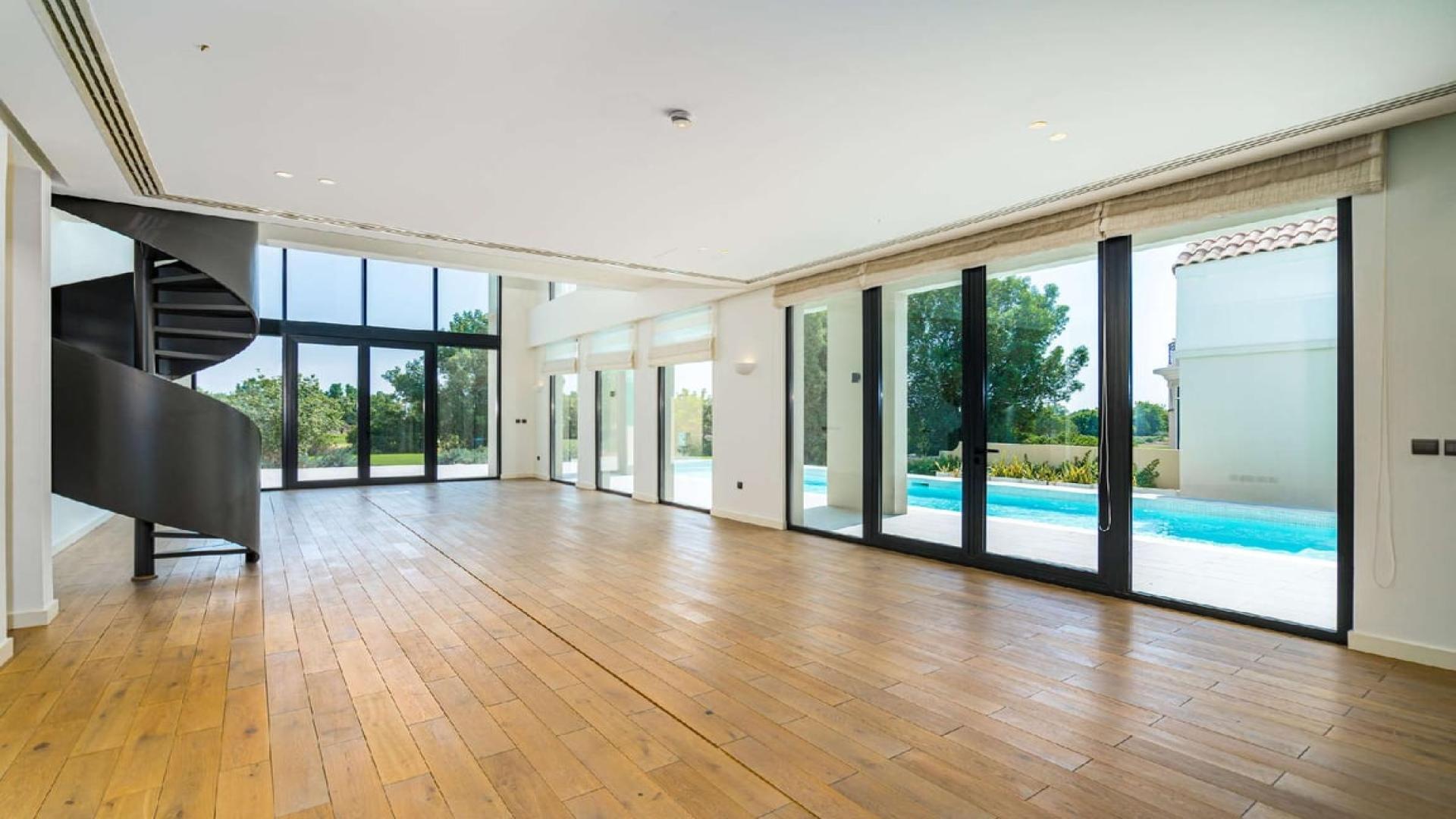 Spacious villa interior with spiral staircase and pool view in Jumeirah Golf Estates