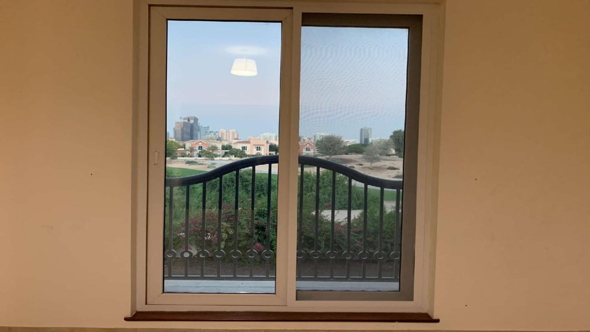 Empty room in 5-bedroom villa, Victory Heights, Dubai, with large windows and garden view