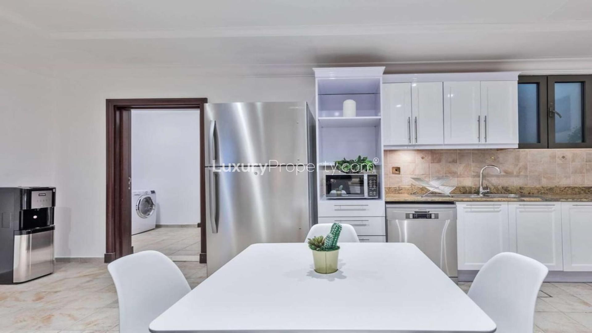 "Private beach villa patio with pool and skyline view, Palm Jumeirah rental.",Modern kitchen in Mediterranean-inspired villa on Palm Jumeirah, featuring sleek appliances and dining area