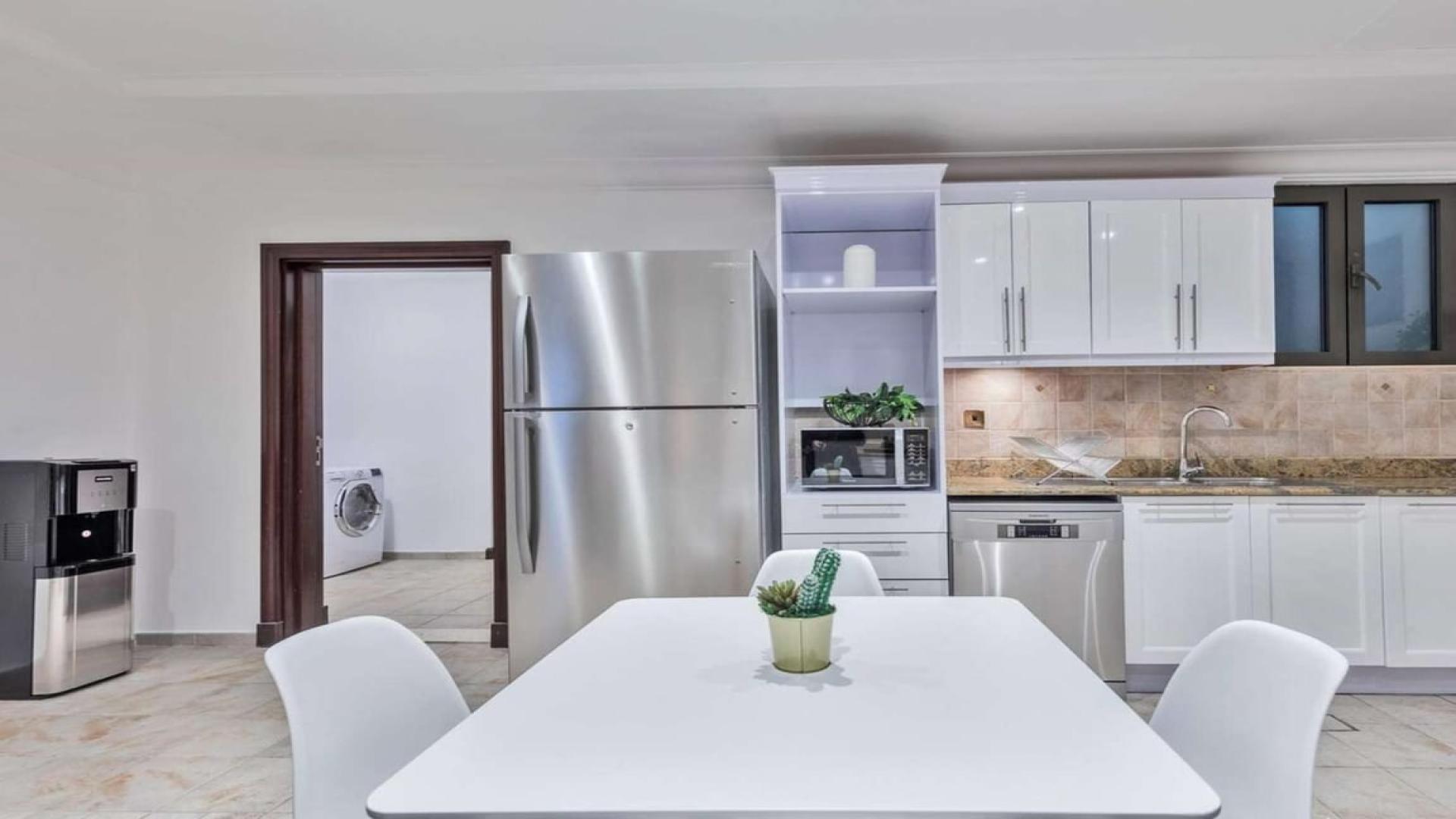 "Private beach villa patio with pool and skyline view, Palm Jumeirah rental.",Modern kitchen in Mediterranean-inspired villa on Palm Jumeirah, featuring sleek appliances and dining area