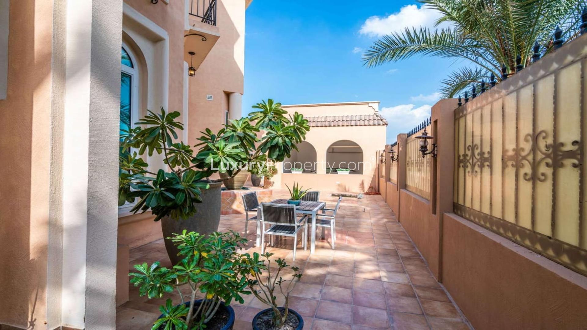 Mediterranean-style villa exterior in Al Sufouh 1, featuring palm trees and stone fencing
