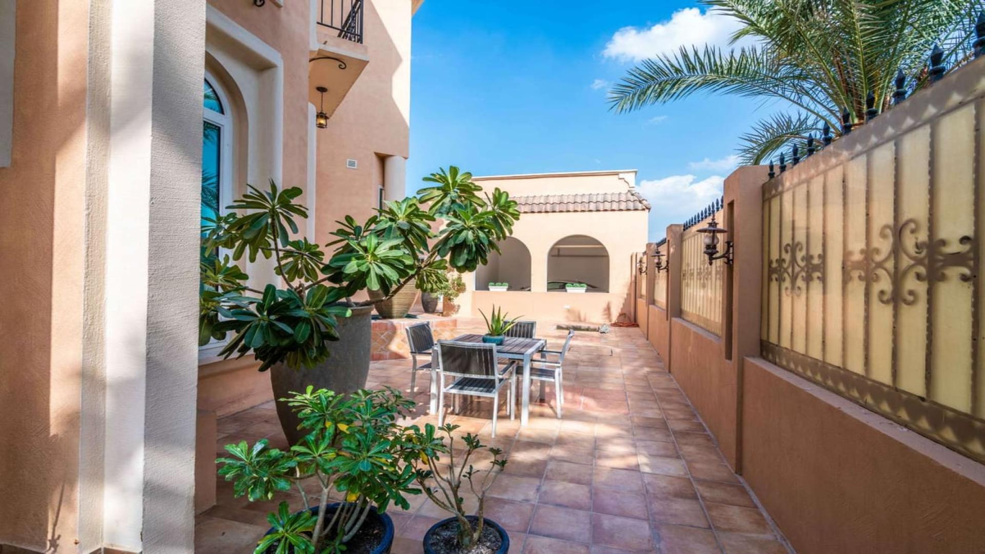 Mediterranean-style villa exterior in Al Sufouh 1, featuring palm trees and stone fencing