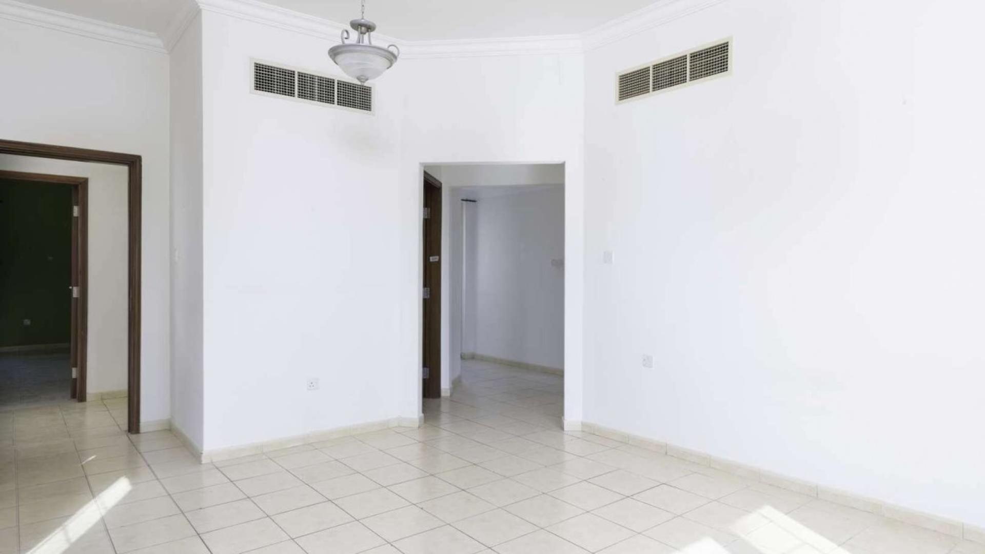 "Elegant staircase in Jumeirah Islands villa, European Clusters, spacious interior, natural light.",Empty living room in Jumeirah Island villa with tiled floors and white walls