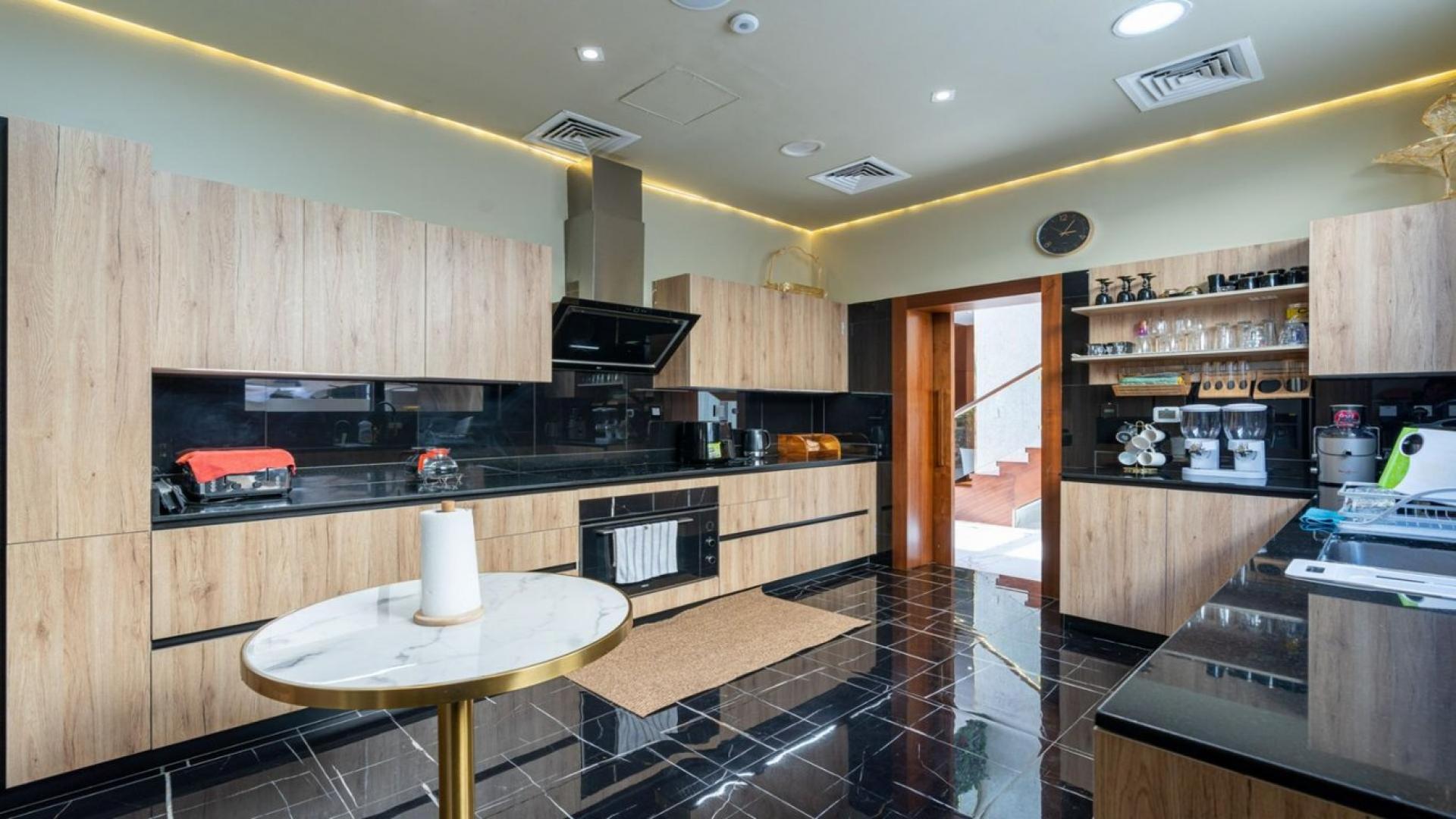 Modern kitchen in upgraded Whitefield villa, Damac Hills, featuring sleek wood cabinetry and appliances