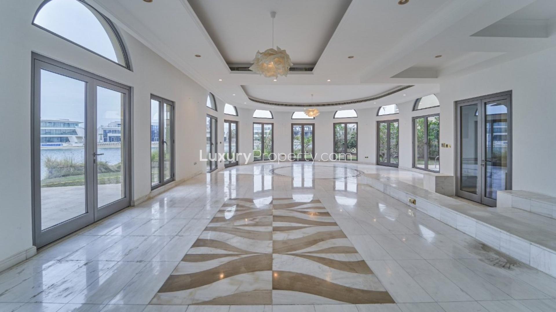 "Beachfront view from luxury villa on Palm Jumeirah, showcasing scenic water and architectural design.",Spacious villa interior with marble floors, large windows, Palm Jumeirah beachfront access