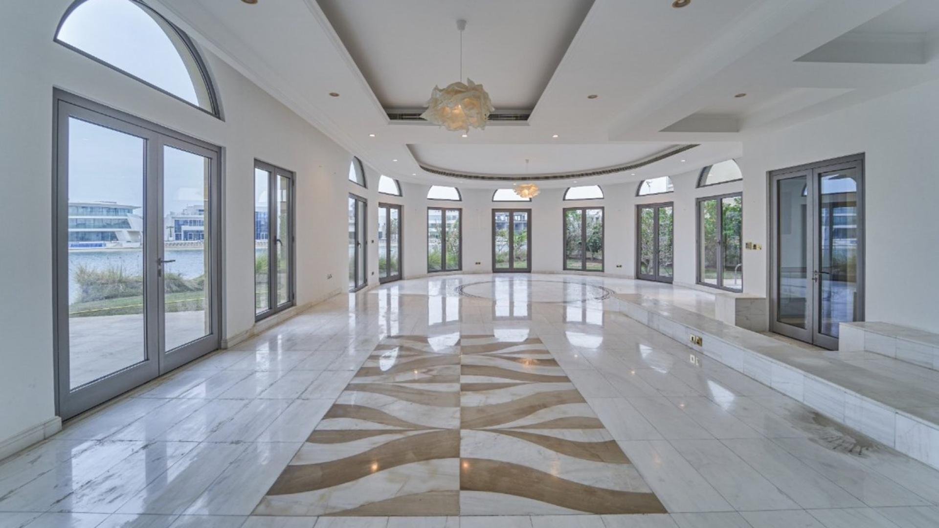 "Beachfront view from luxury villa on Palm Jumeirah, showcasing scenic water and architectural design.",Spacious villa interior with marble floors, large windows, Palm Jumeirah beachfront access