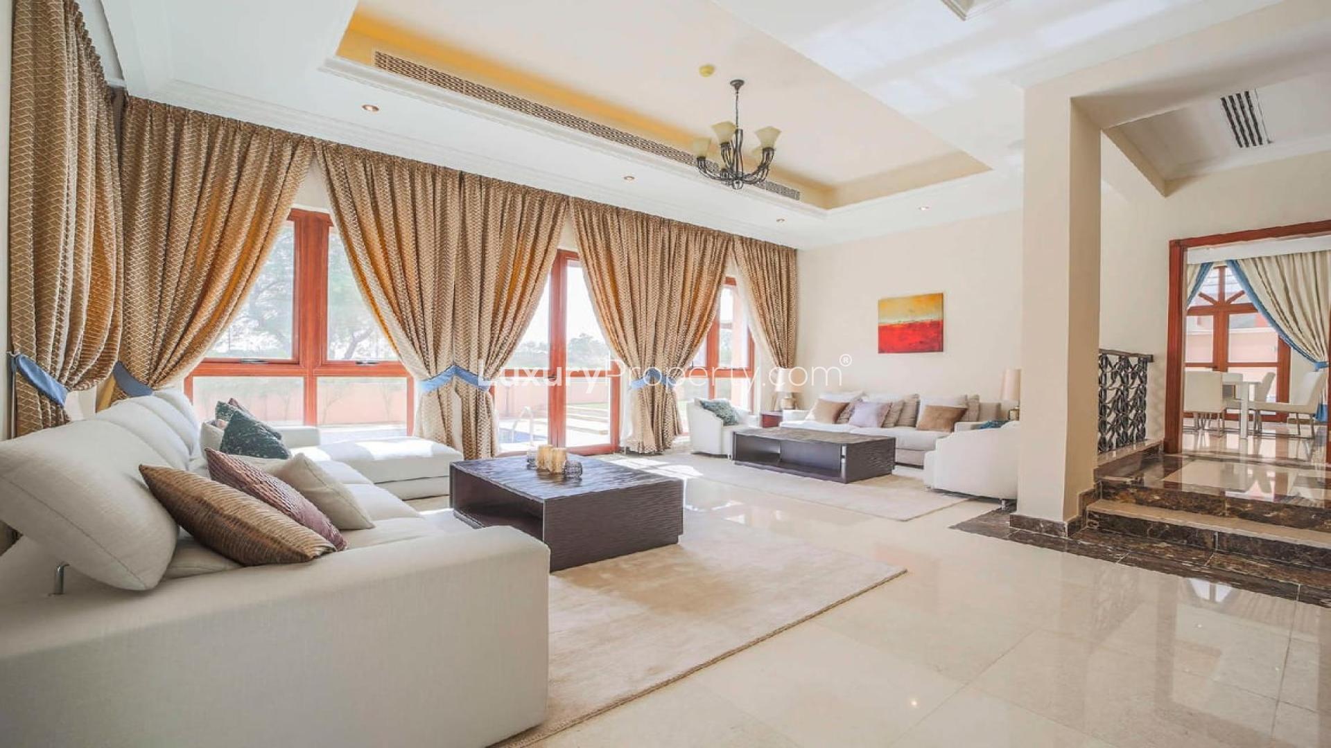 Luxurious living room with large windows and elegant furnishings in Jumeirah Golf Estates villa