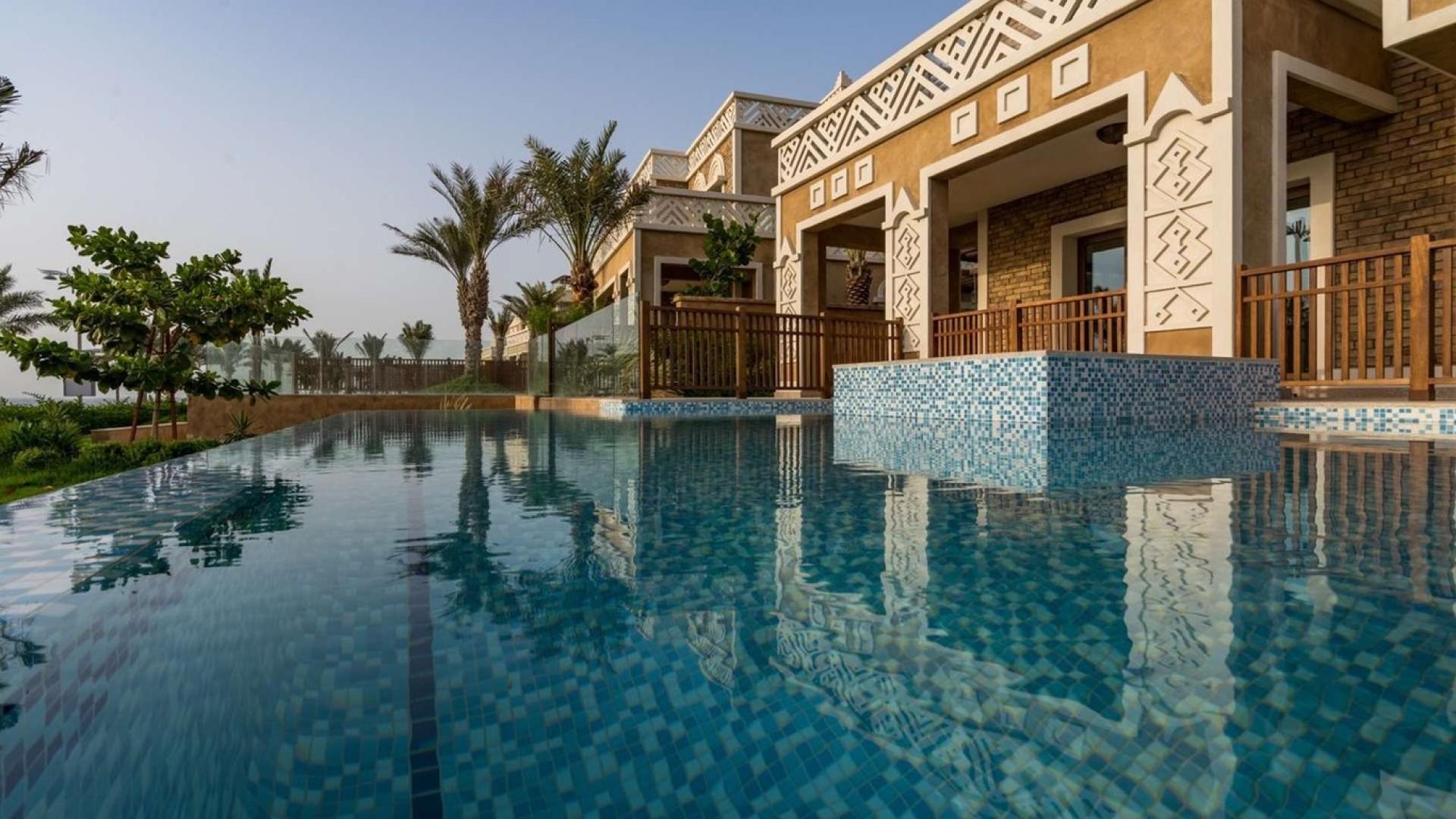 "Majestic villa terrace view of sunset over pool, Palm Jumeirah, Kingdom of Sheba.","Majestic villa with stunning pool view in Kingdom of Sheba, Palm Jumeirah, for sale.",Spacious living area with large windows and ocean view in Palm Jumeirah villa
