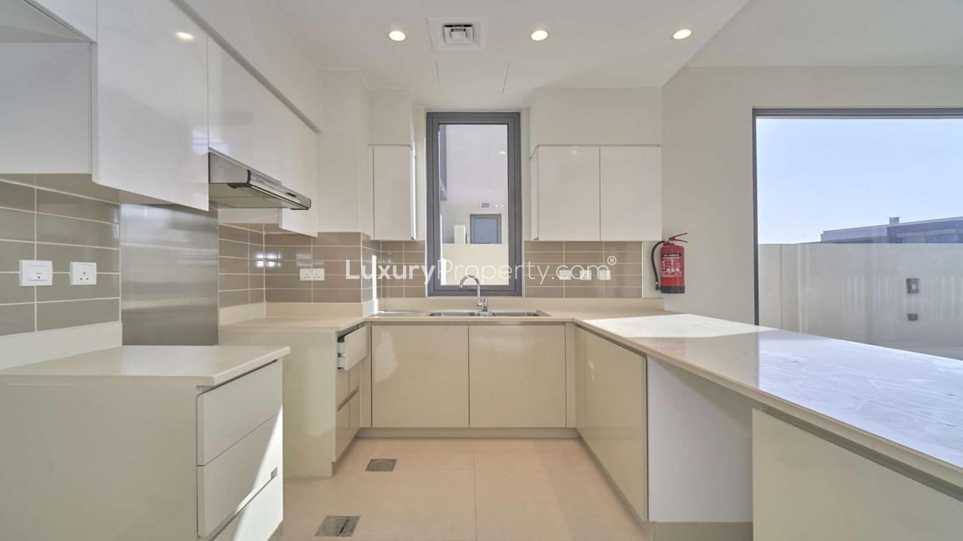 "Spacious villa exterior view in Maple at Dubai Hills Estate, near pool and entrance.",Modern kitchen in 5-bedroom villa, Maple at Dubai Hills Estate, spacious countertops, bright lighting