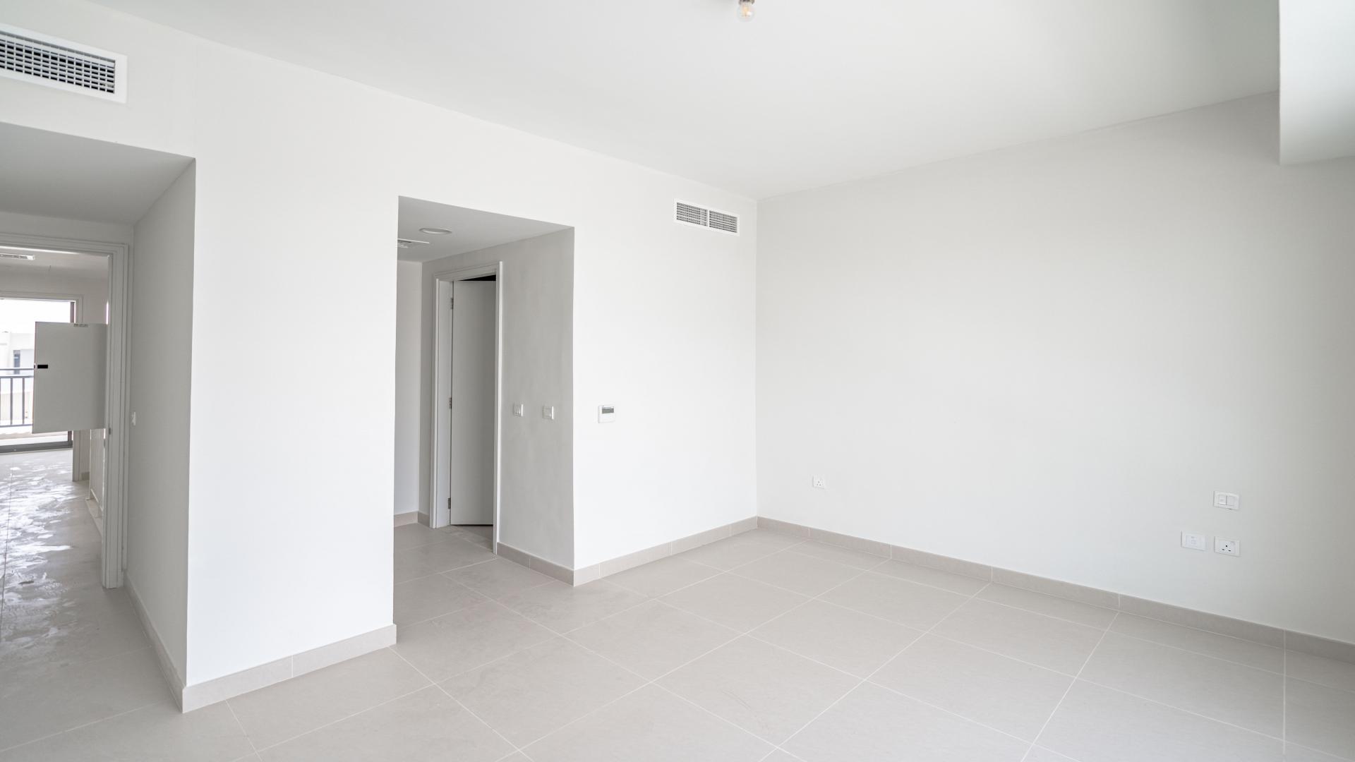 Empty room in townhouse, Maple at Dubai Hills Estate, with modern white interior and tile flooring