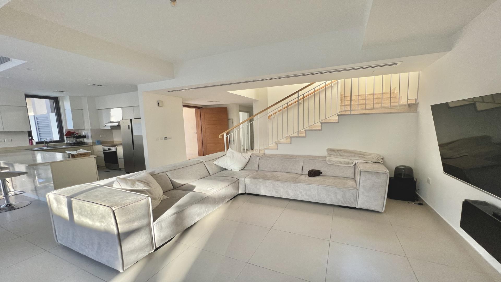 Modern living room in 5-bedroom villa, Maple 2, Dubai Hills Estate, with sleek staircase