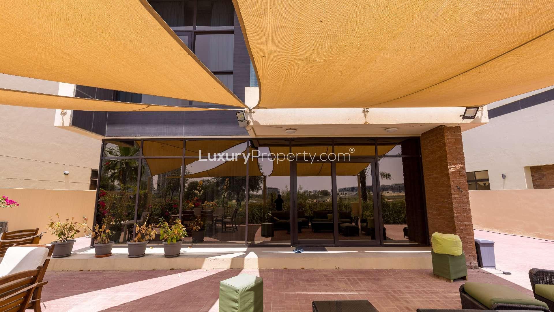 Spacious patio with seating, shaded canopy, overlooking golf course at Damac Hills villa