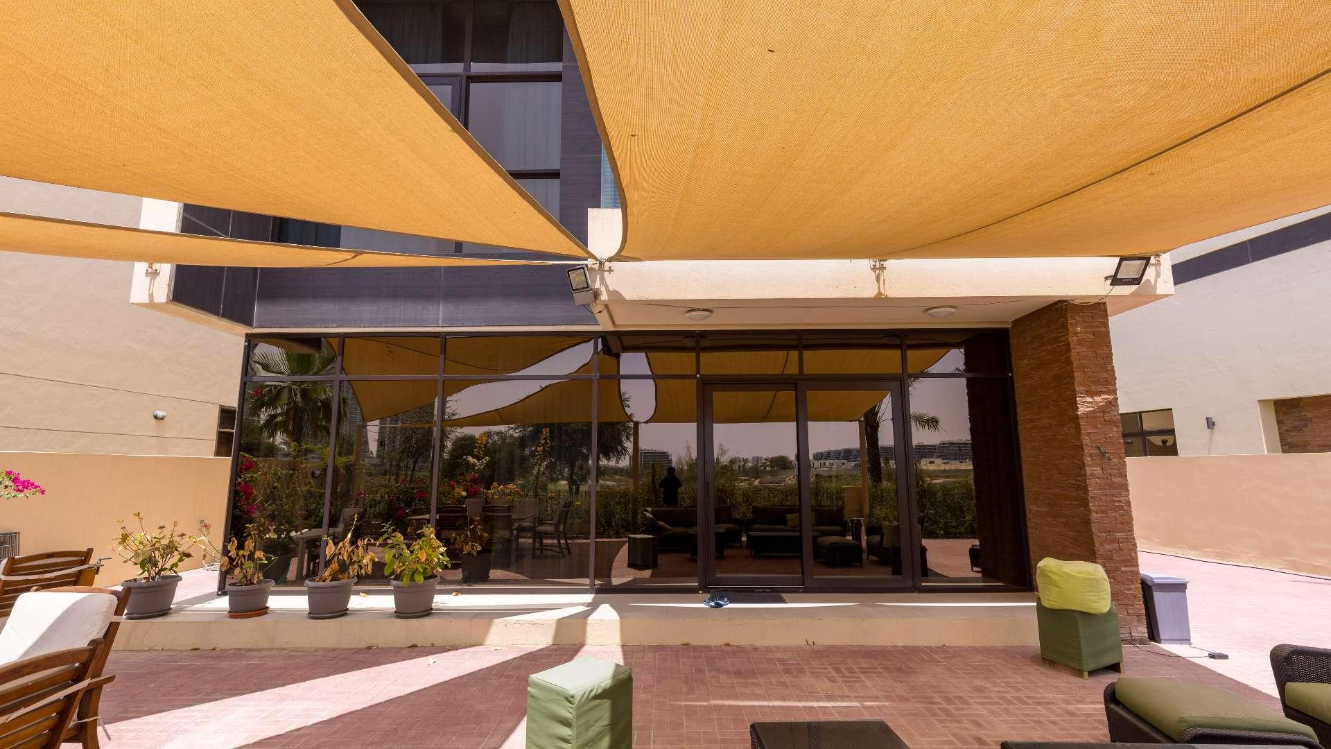 Spacious patio with seating, shaded canopy, overlooking golf course at Damac Hills villa