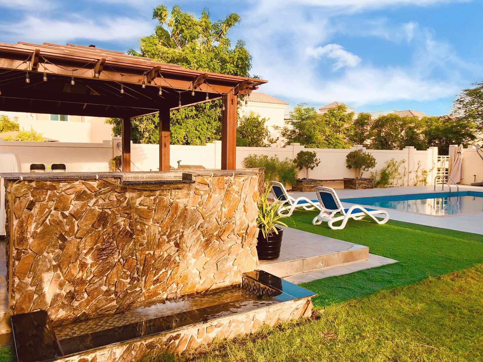 "Spacious white built-in wardrobes in 5-bedroom C2 villa, Victory Heights, Dubai Sports City.",Luxurious villa in Victory Heights with pool, stone waterfall, and outdoor seating area