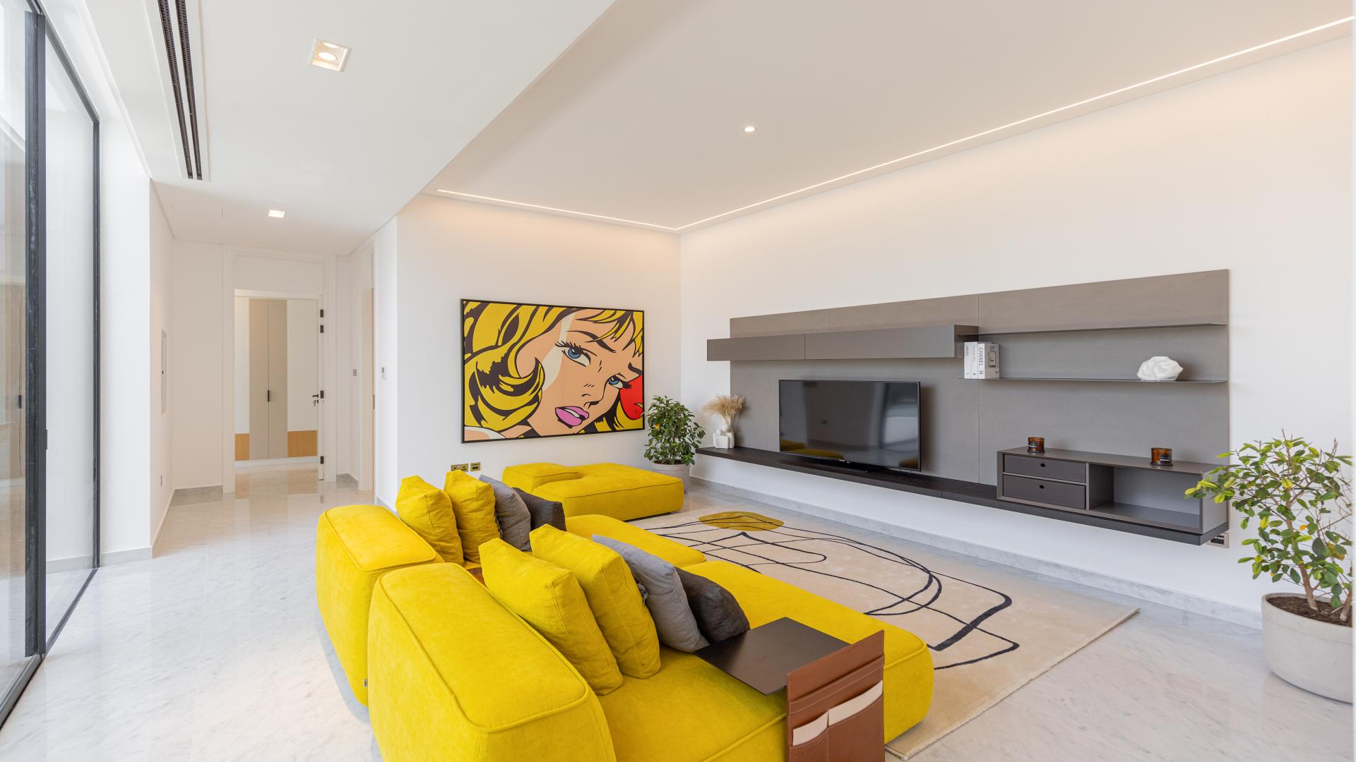 "Chorisia 1 Villas in Al Barari, lush greenery and modern architecture, luxury rental property.",Modern living room in luxury Al Barari villa with vibrant yellow sofa and artwork