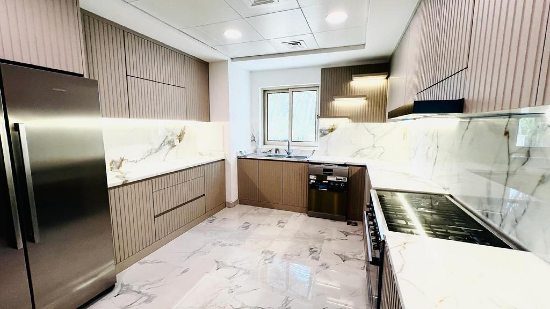 Modern kitchen in upgraded Jumeirah Islands villa with marble countertops and integrated appliances