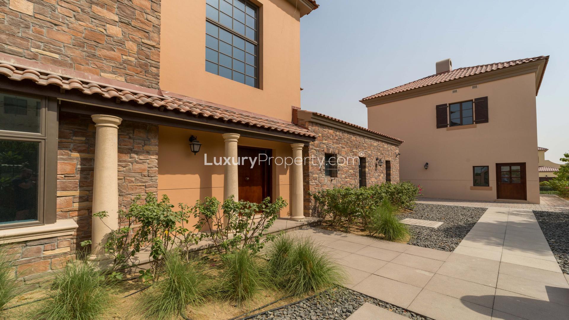 Villa exterior in Jumeirah Golf Estates Fire community, featuring spacious driveway and landscaping