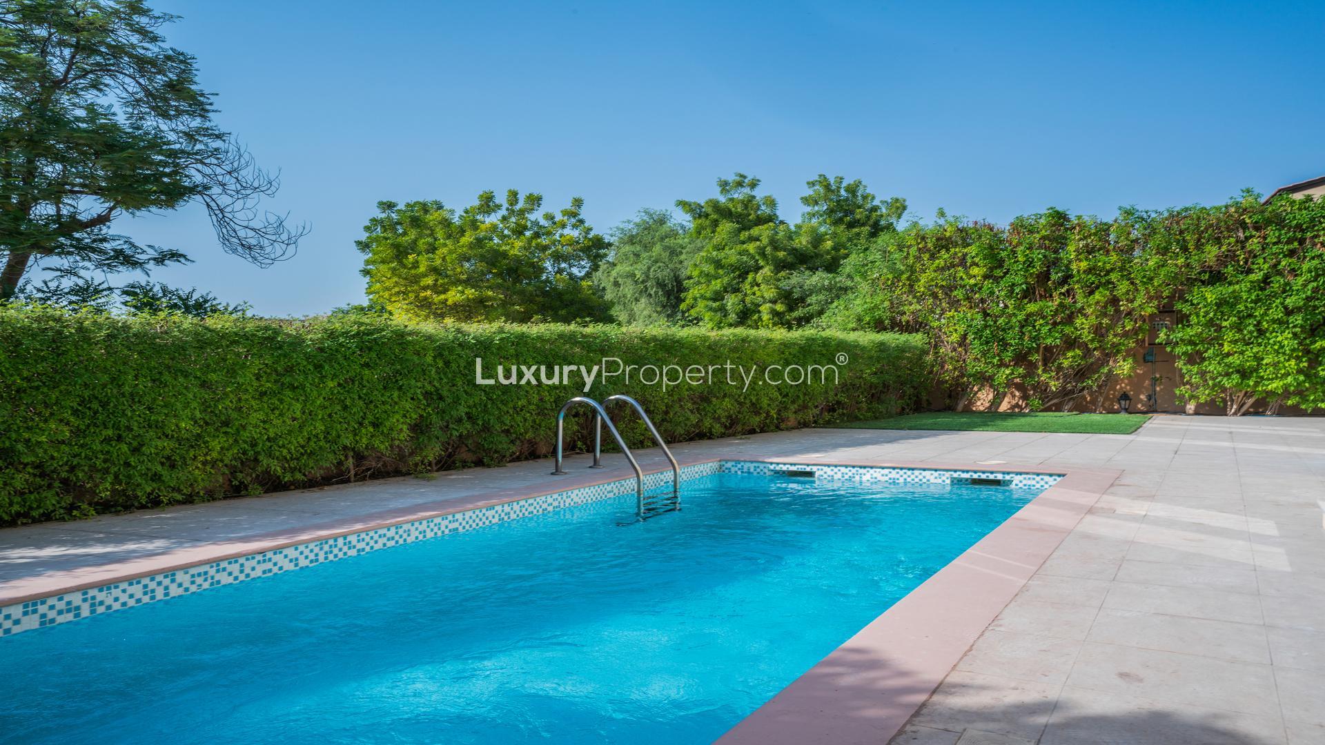 "Upgraded 5-bedroom villa exterior in Jumeirah Golf Estates, Fire community, lush greenery view.",Outdoor pool in Jumeirah Golf Estates villa, lush greenery, sunny day, Fire sub-community