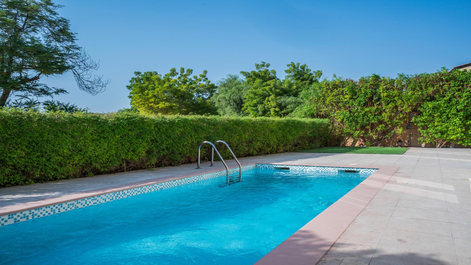 "Upgraded 5-bedroom villa exterior in Jumeirah Golf Estates, Fire community, lush greenery view.",Outdoor pool in Jumeirah Golf Estates villa, lush greenery, sunny day, Fire sub-community