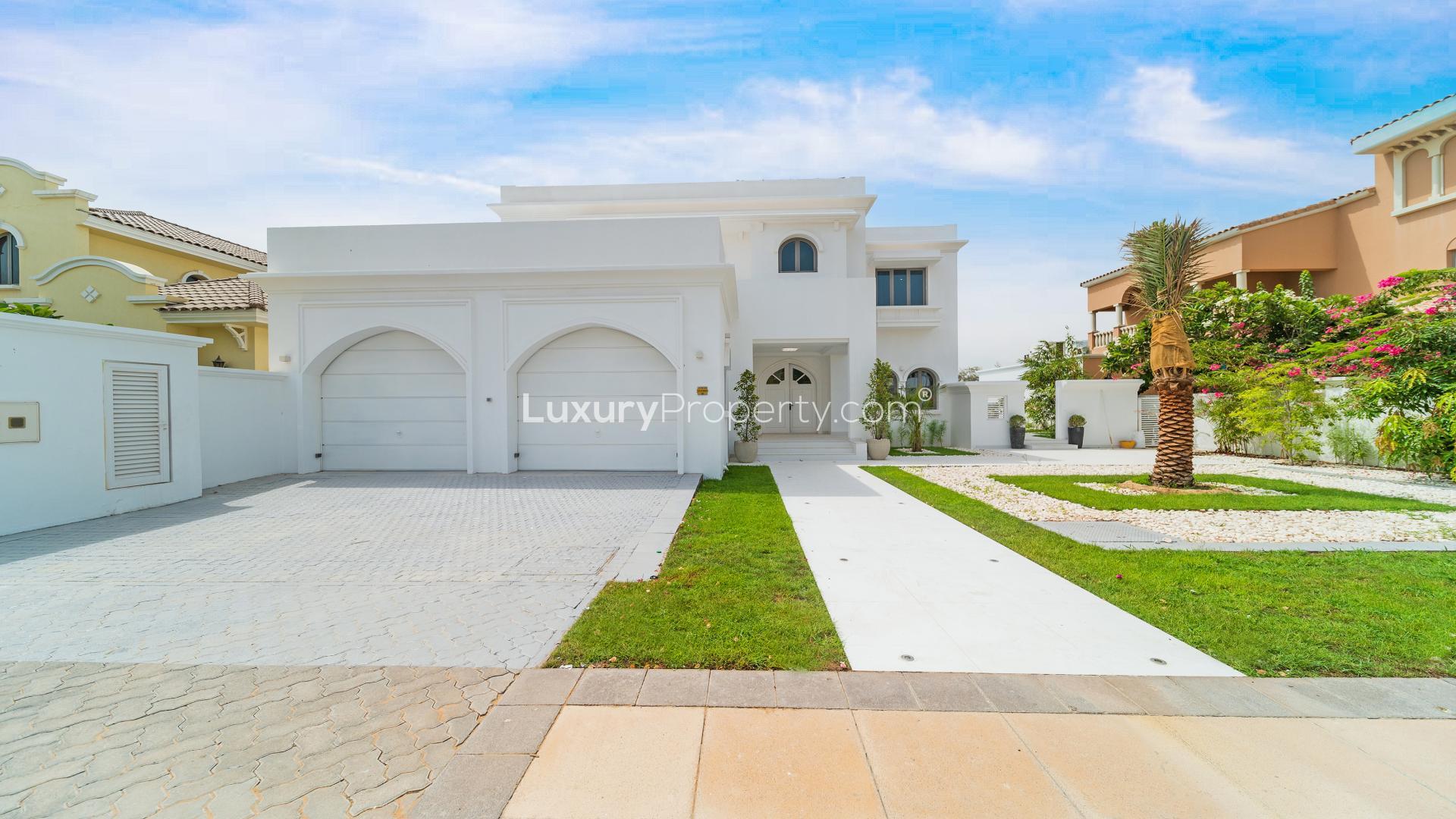 Beachfront patio view from Palm Jumeirah villa with sun loungers and lush greenery