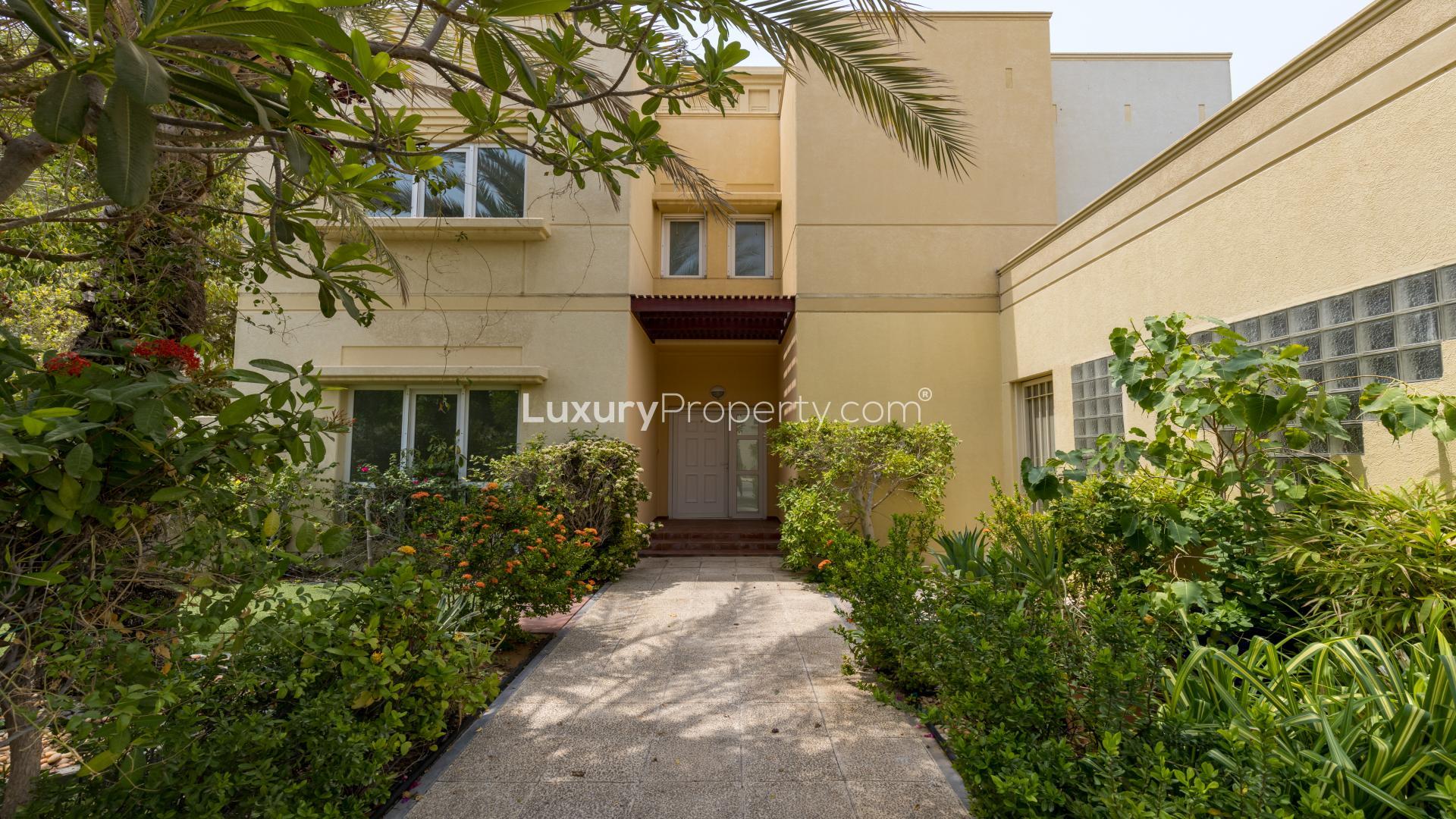 Exterior view of villa with lush greenery and driveway in Meadows 9 community