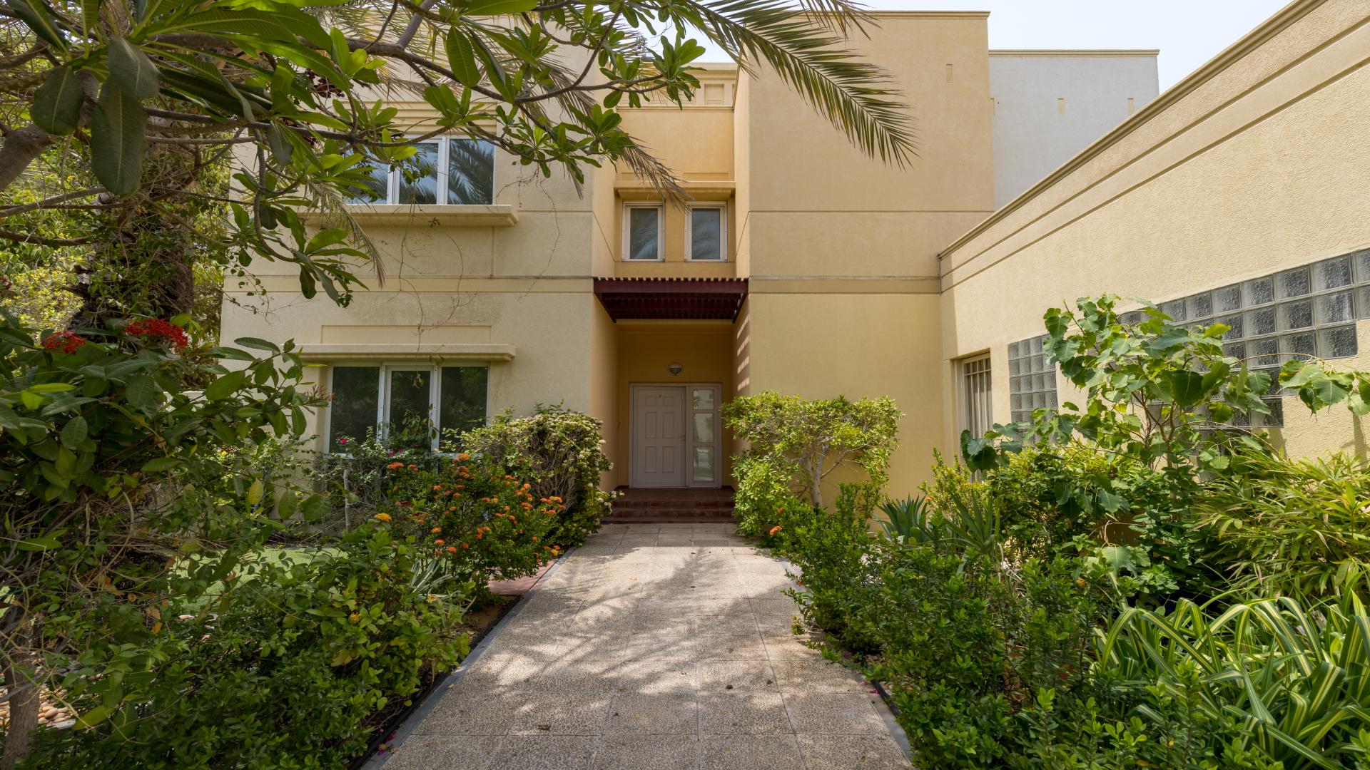 Exterior view of villa with lush greenery and driveway in Meadows 9 community