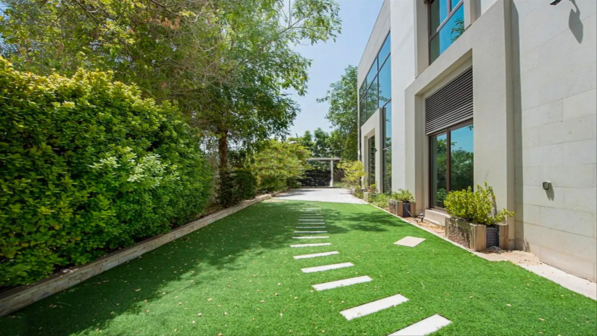 Modern villa exterior in Meydan Gated Community, featuring lush greenery and contemporary design