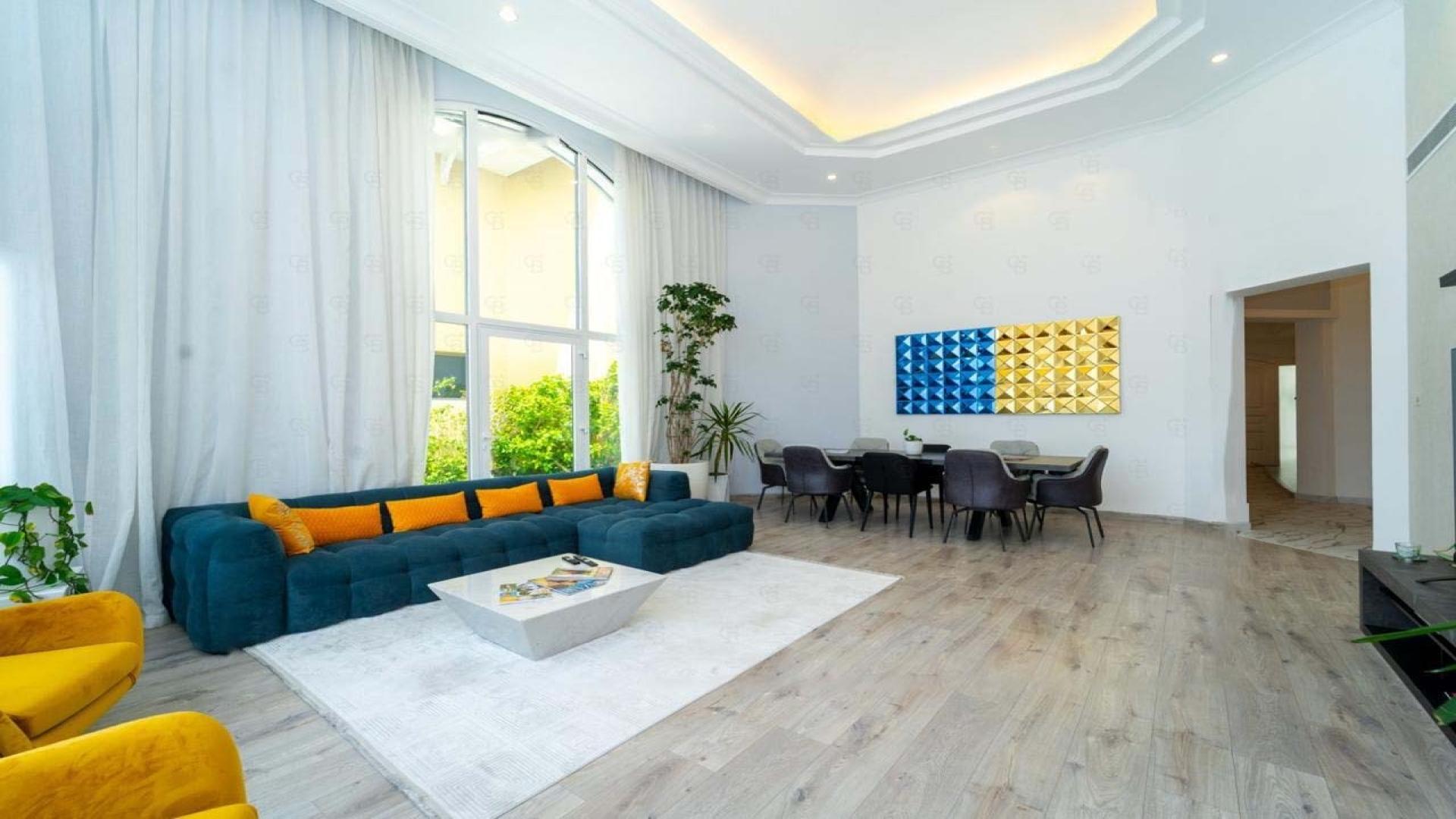 Furnished living room in Palm Jumeirah villa with large windows and modern decor