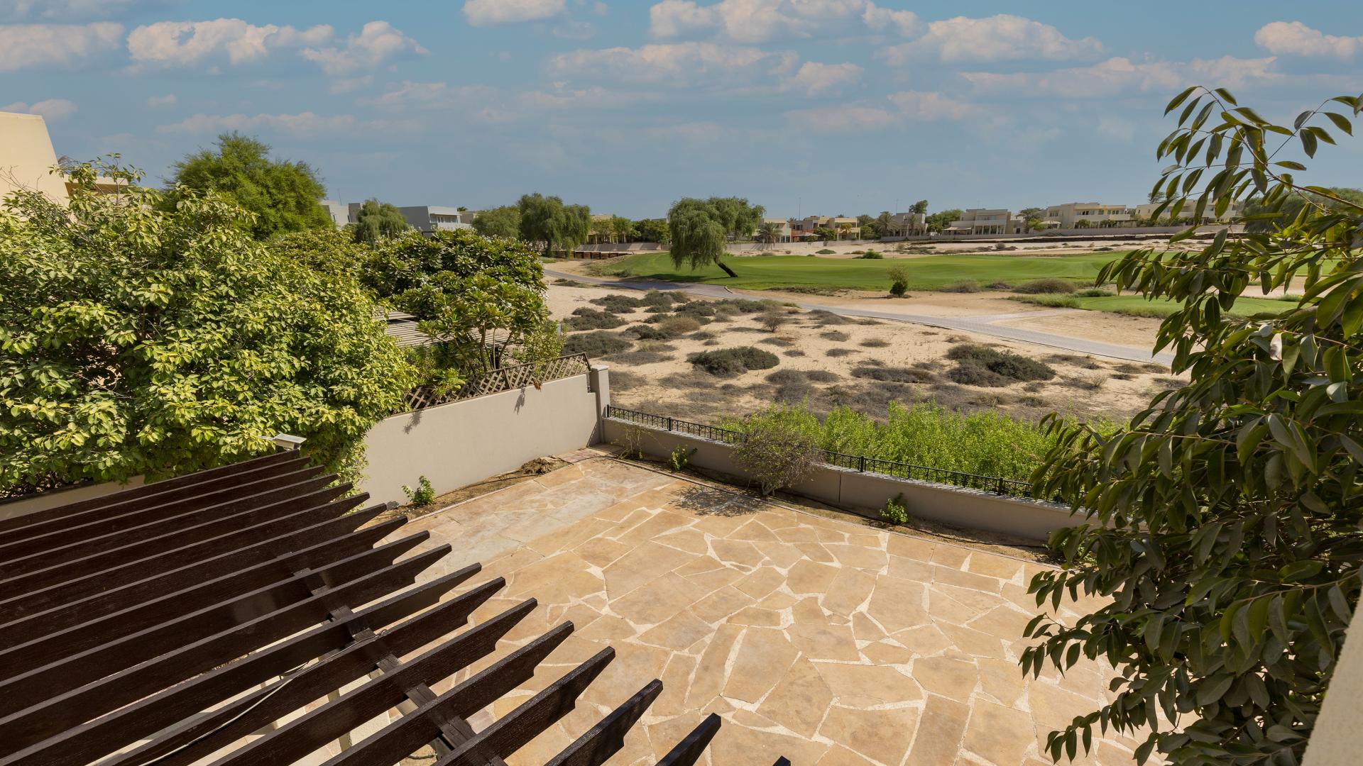 Alt text: "Villa patio with lush greenery overlooking Arabian Ranches golf course in Savannah community.",Exterior view of spacious villa with patio in Savannah, Arabian Ranches, available for rent