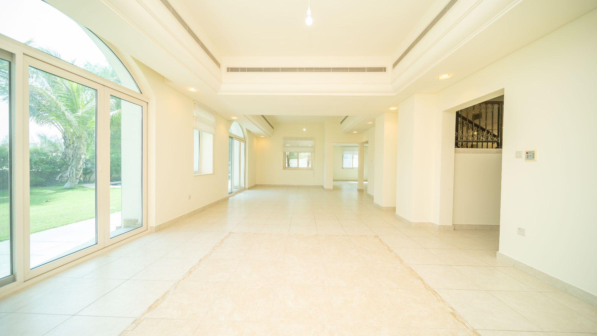 "Spacious 5-bedroom villa with private pool in Victory Heights, Dubai Sports City.",Spacious living area with garden view in Victory Heights villa, Dubai Sports City