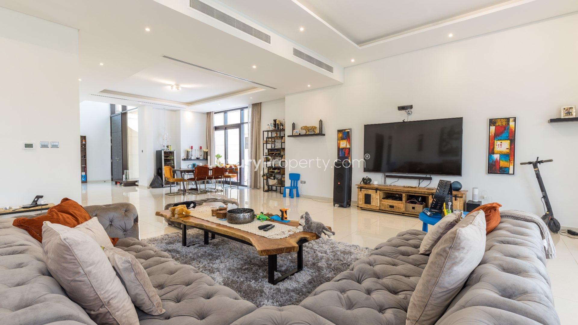 Luxurious living room in 5-bedroom villa, Damac Hills, featuring plush sofa and garden view