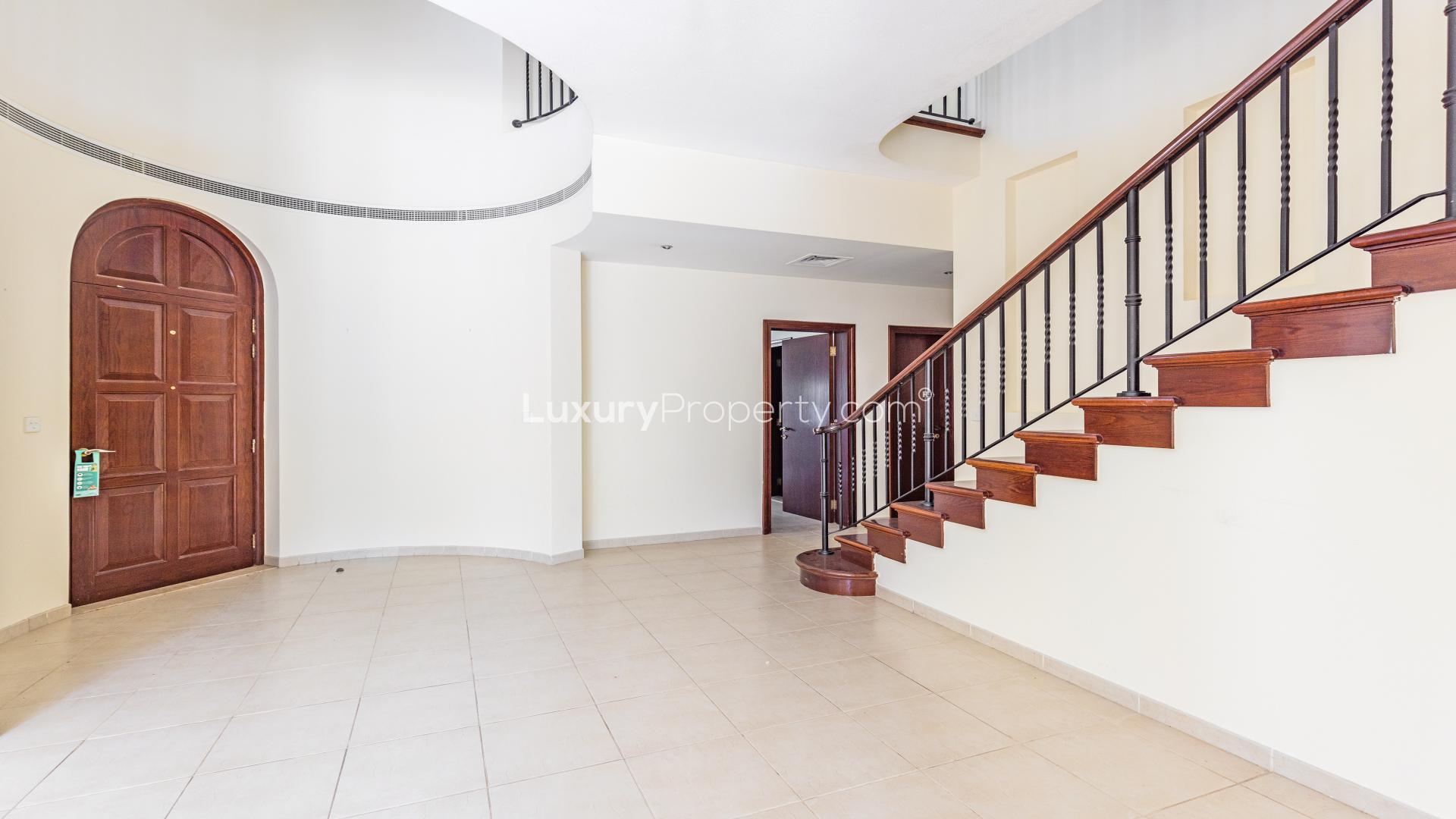 Covered patio with arches overlooking lush garden in Alvorada, Arabian Ranches villa