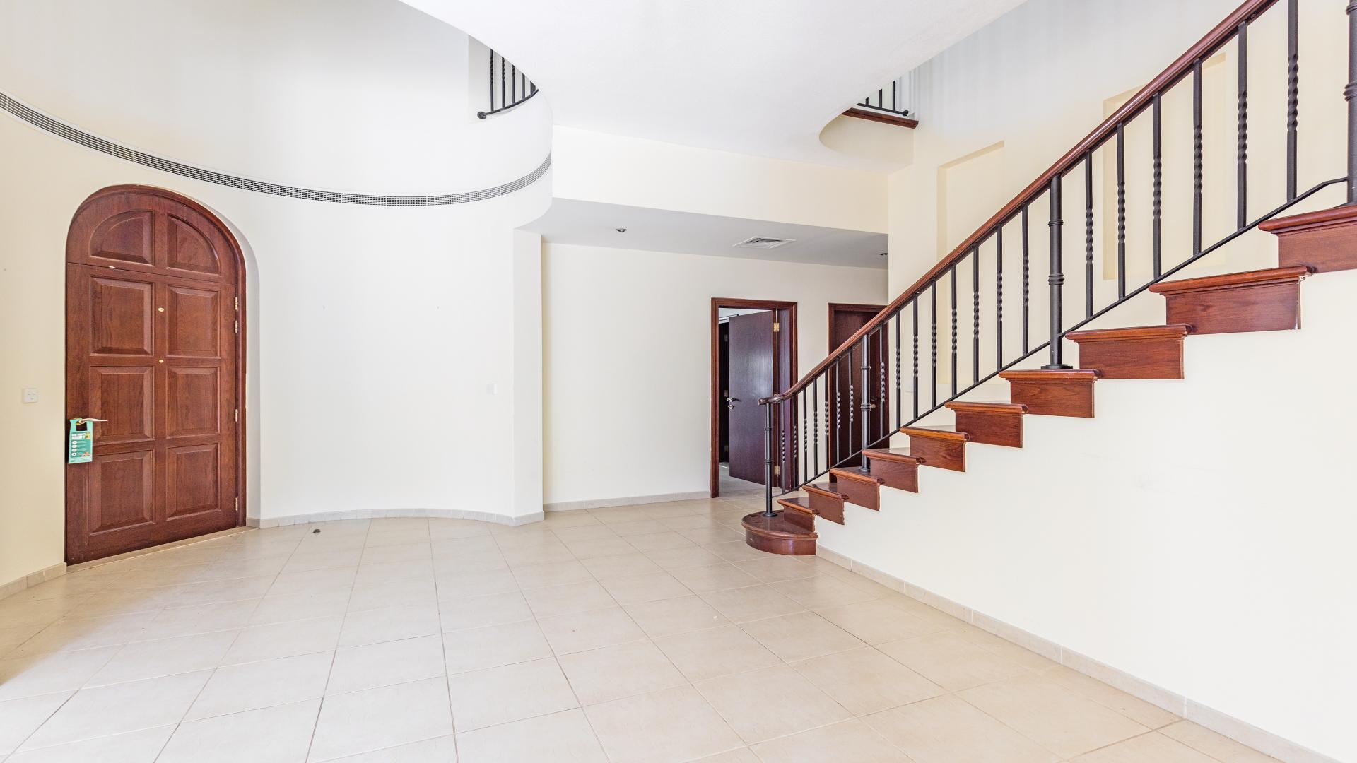 Covered patio with arches overlooking lush garden in Alvorada, Arabian Ranches villa
