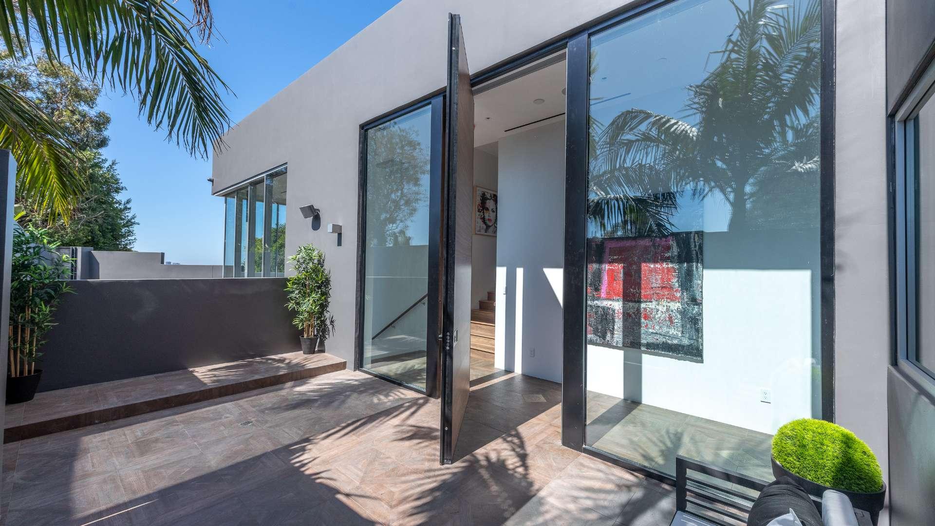 Luxurious Beverly Hills villa exterior with palm trees and modern architecture, featuring driveway