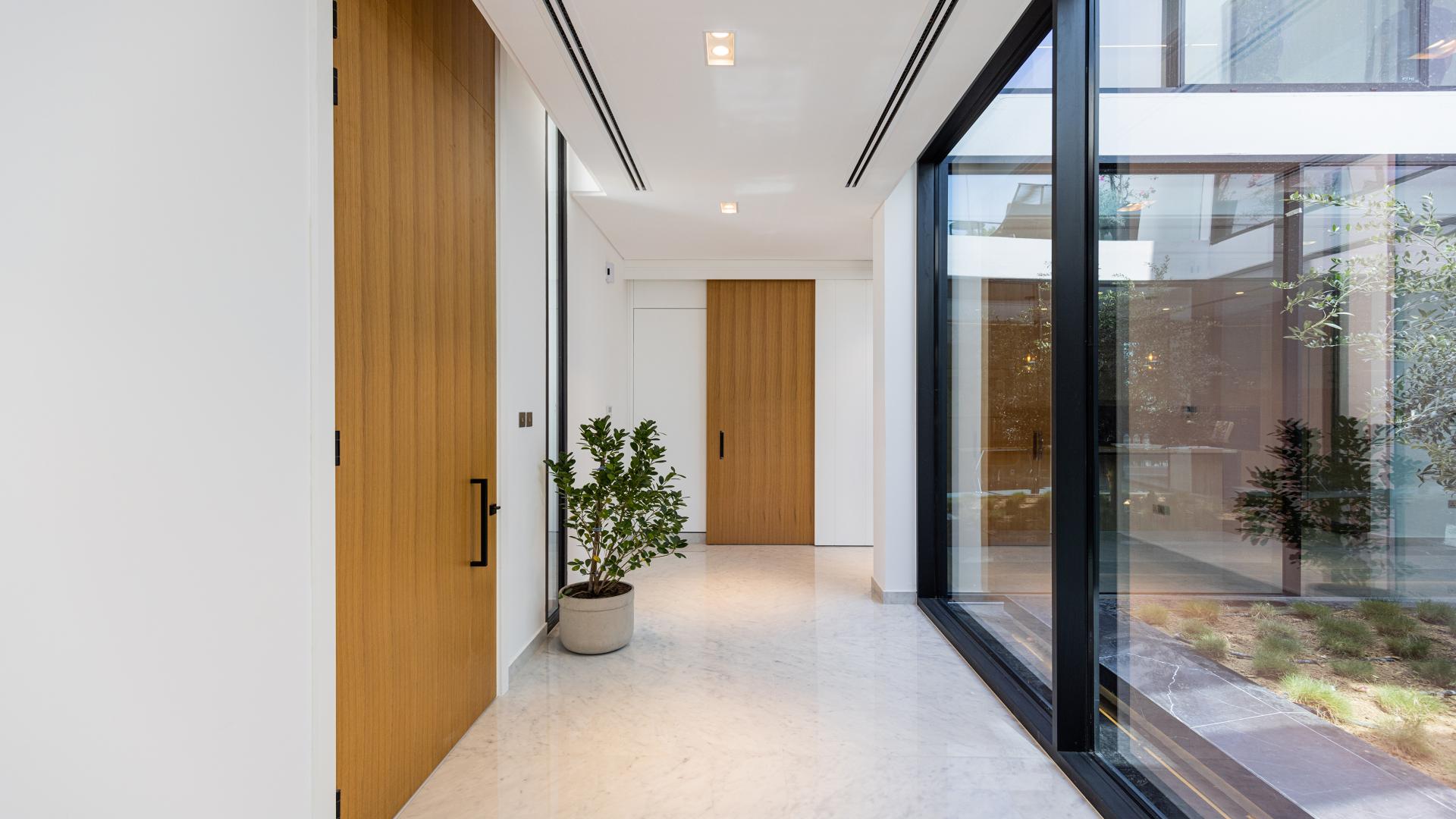 "Chorisia 1 Villas view, lush garden, and serene water feature in Al Barari community.",Modern hallway with glass walls in Al Barari villa, Chorisia 1, Dubai