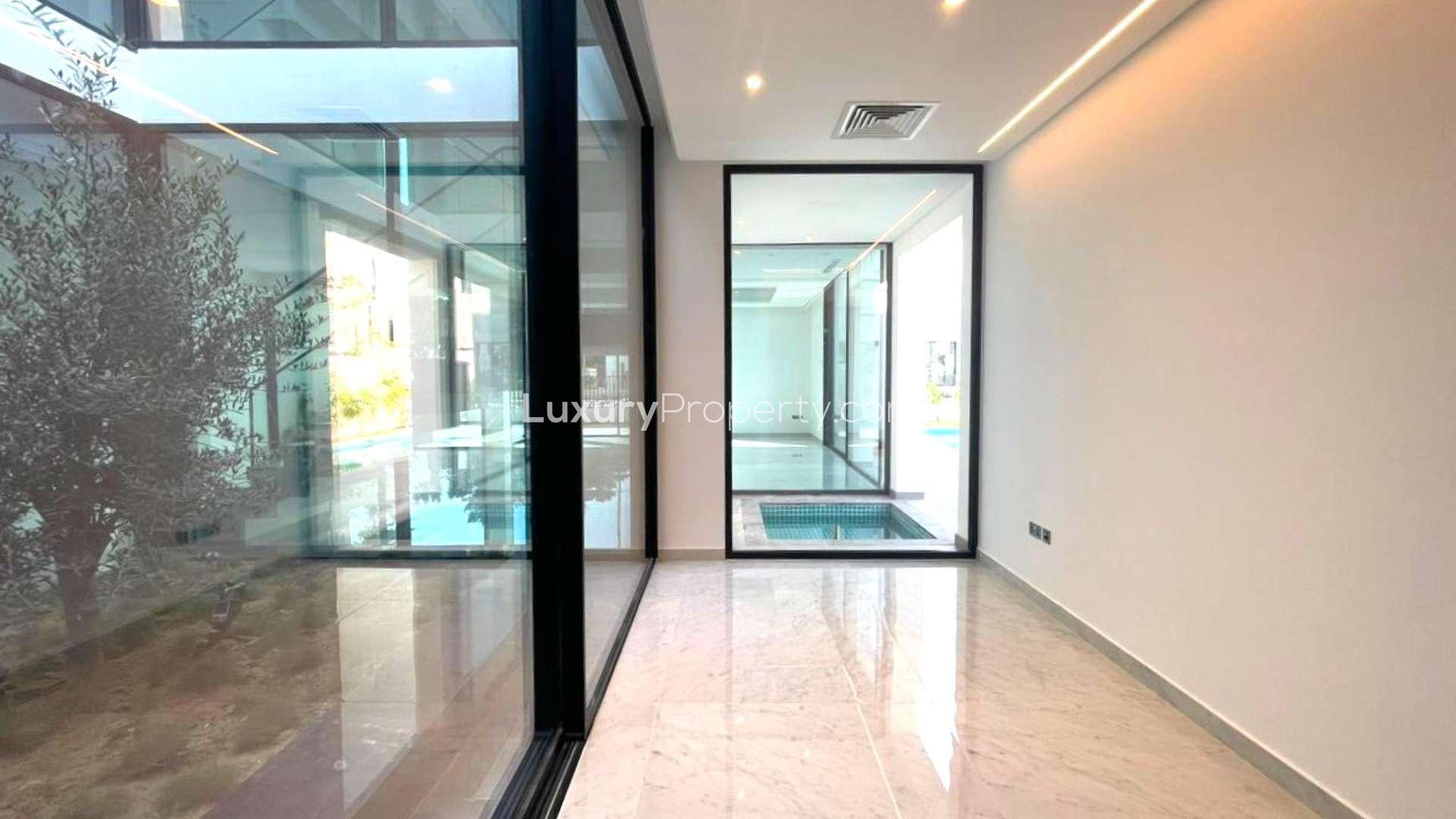 Modern living room in Al Barari villa with large windows and garden view