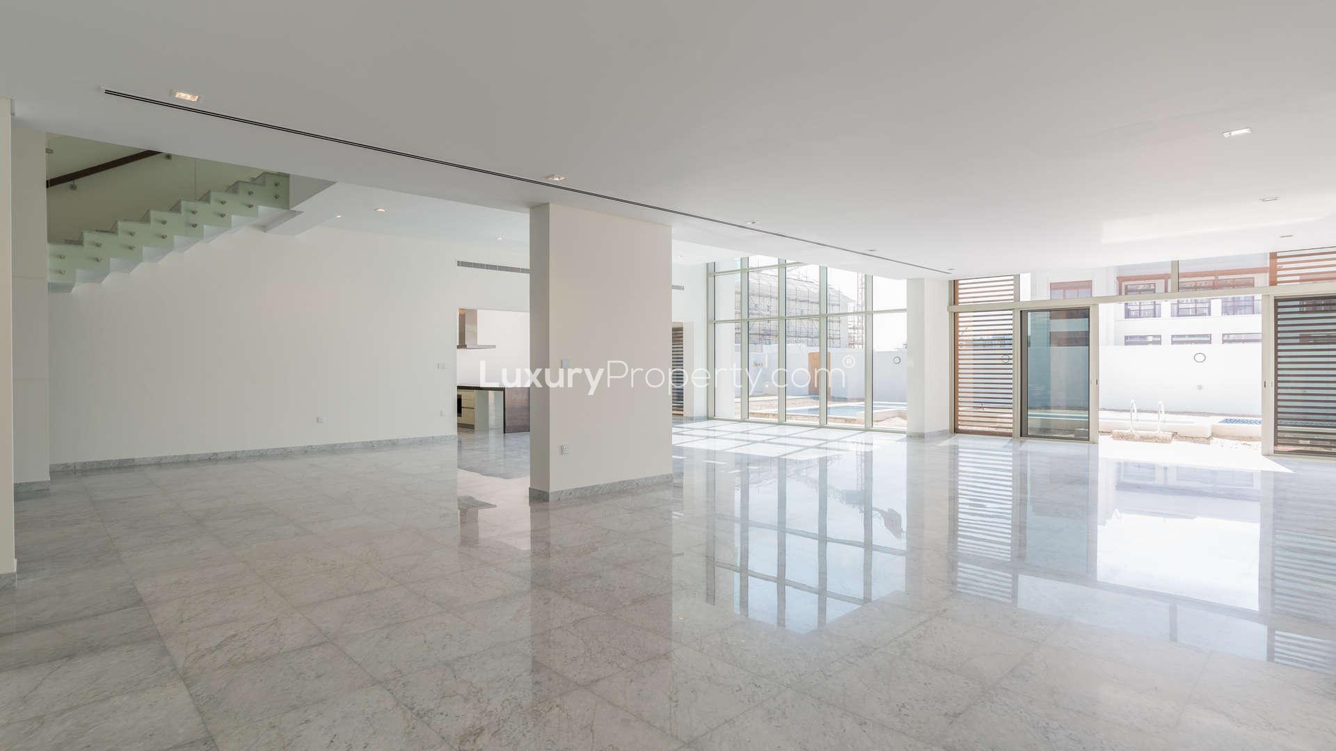 Modern open-plan interior of luxury District One villa with marble flooring and glass staircase