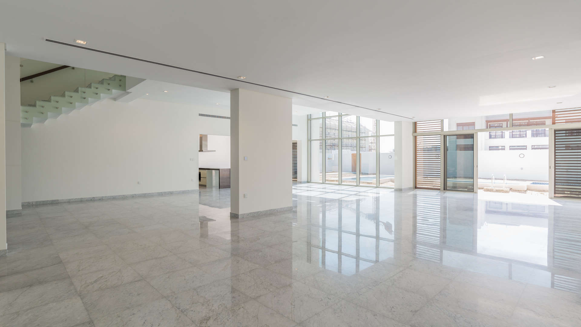 Modern open-plan interior of luxury District One villa with marble flooring and glass staircase
