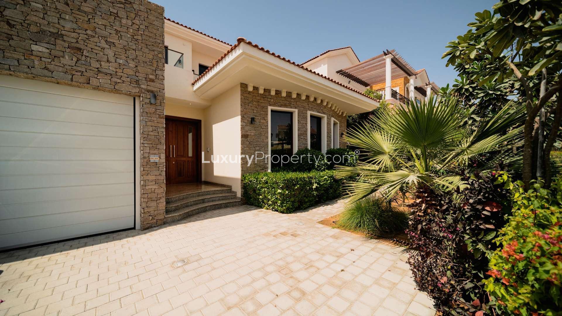 "View from modern villa in Jumeirah Golf Estates, overlooking lush greenery and pool area.",Modern villa exterior in Wildflower, Jumeirah Golf Estates, featuring lush landscaping and stone facade