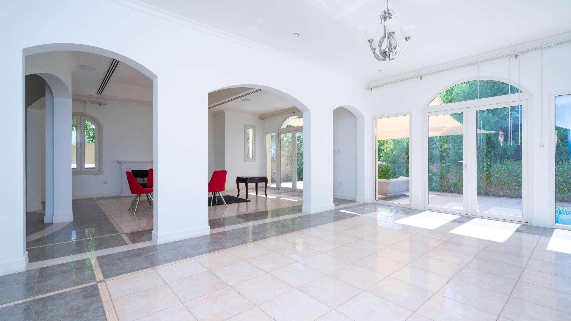 Bright living room with pool view in upgraded Jumeirah Golf Estates villa for sale