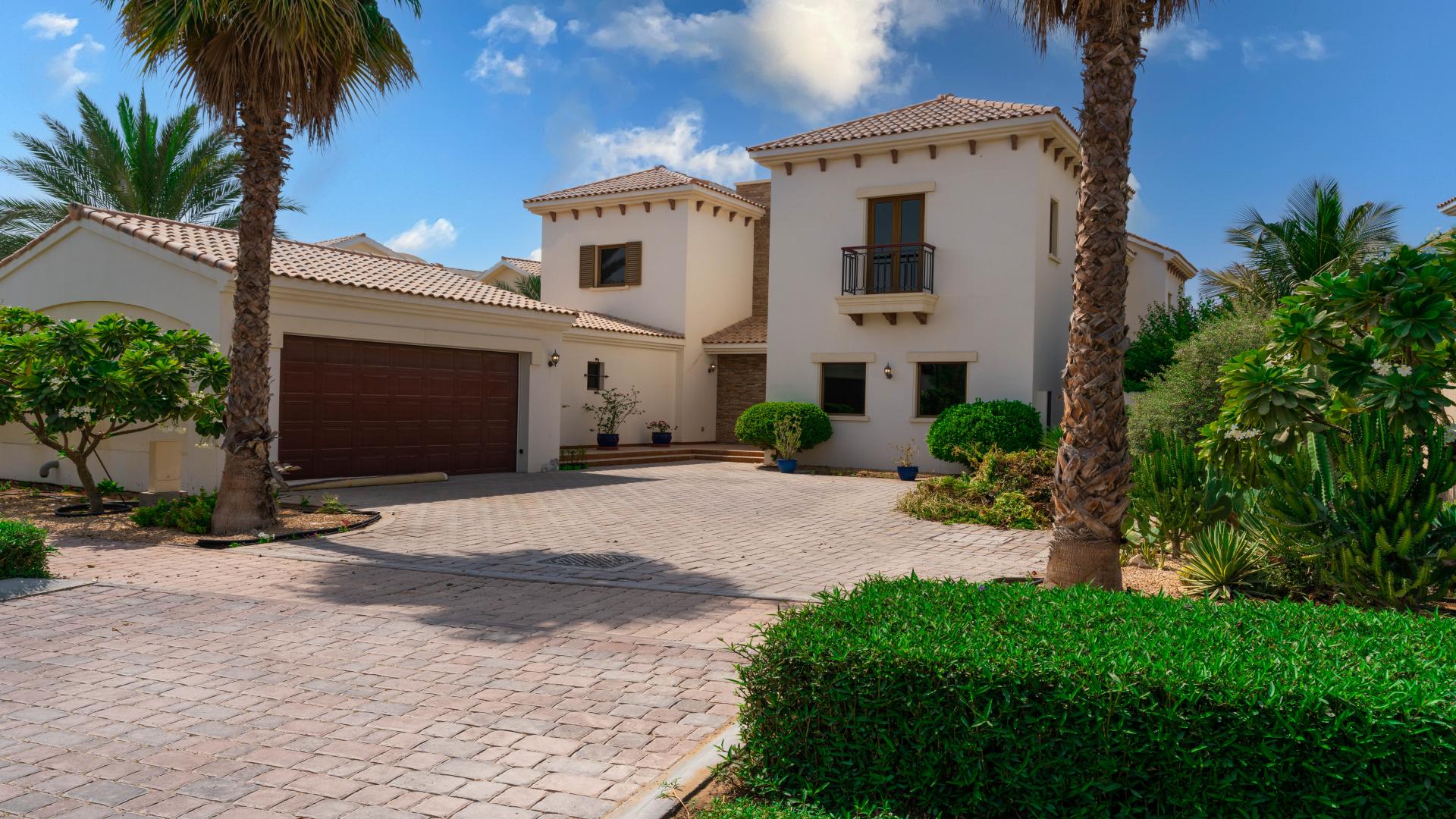 Exterior of Jumeirah Golf Estates villa with garden and pergola, for sale