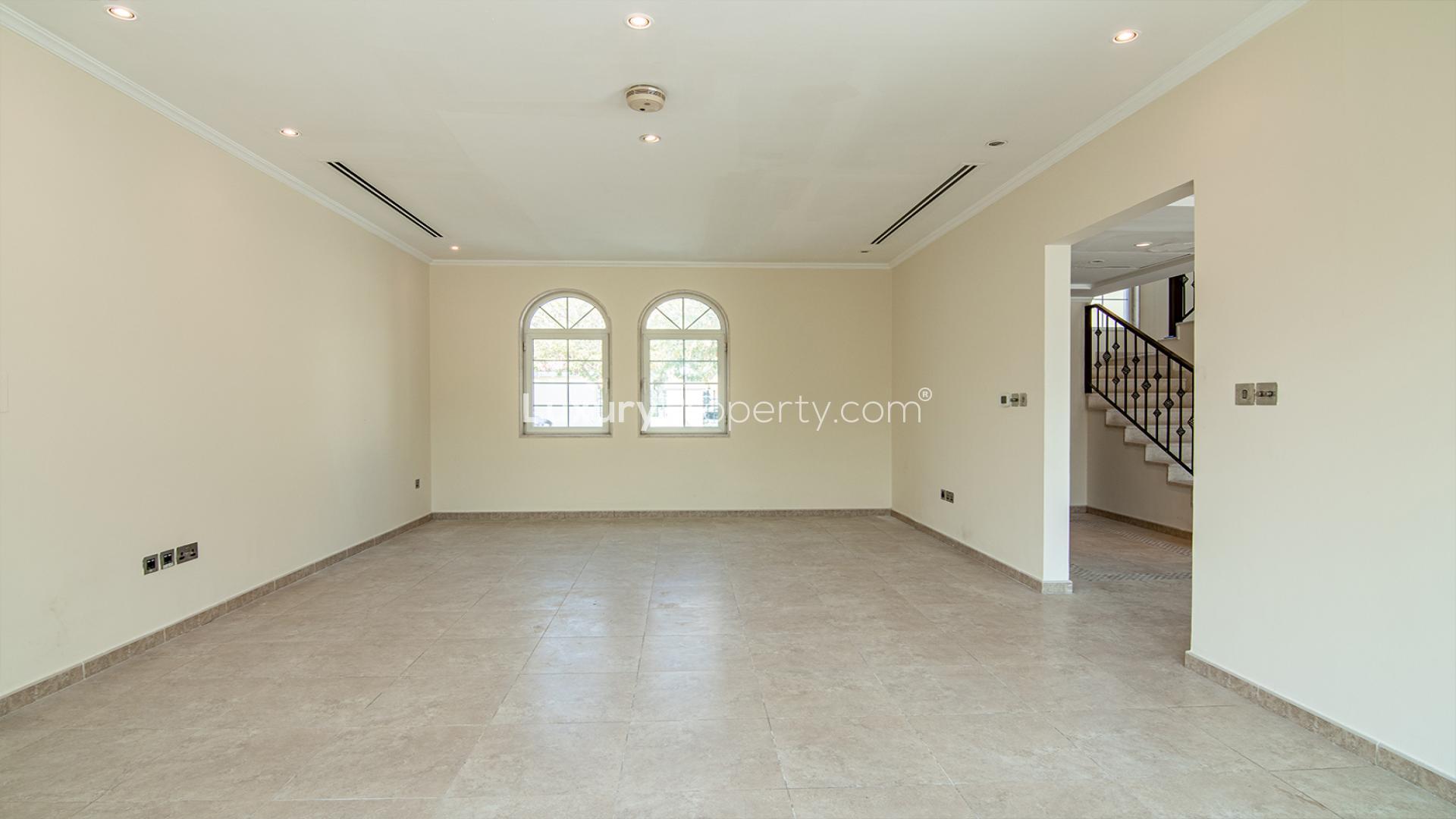 Empty living room in Legacy 3-bed villa, Jumeirah Park, featuring large windows and staircase