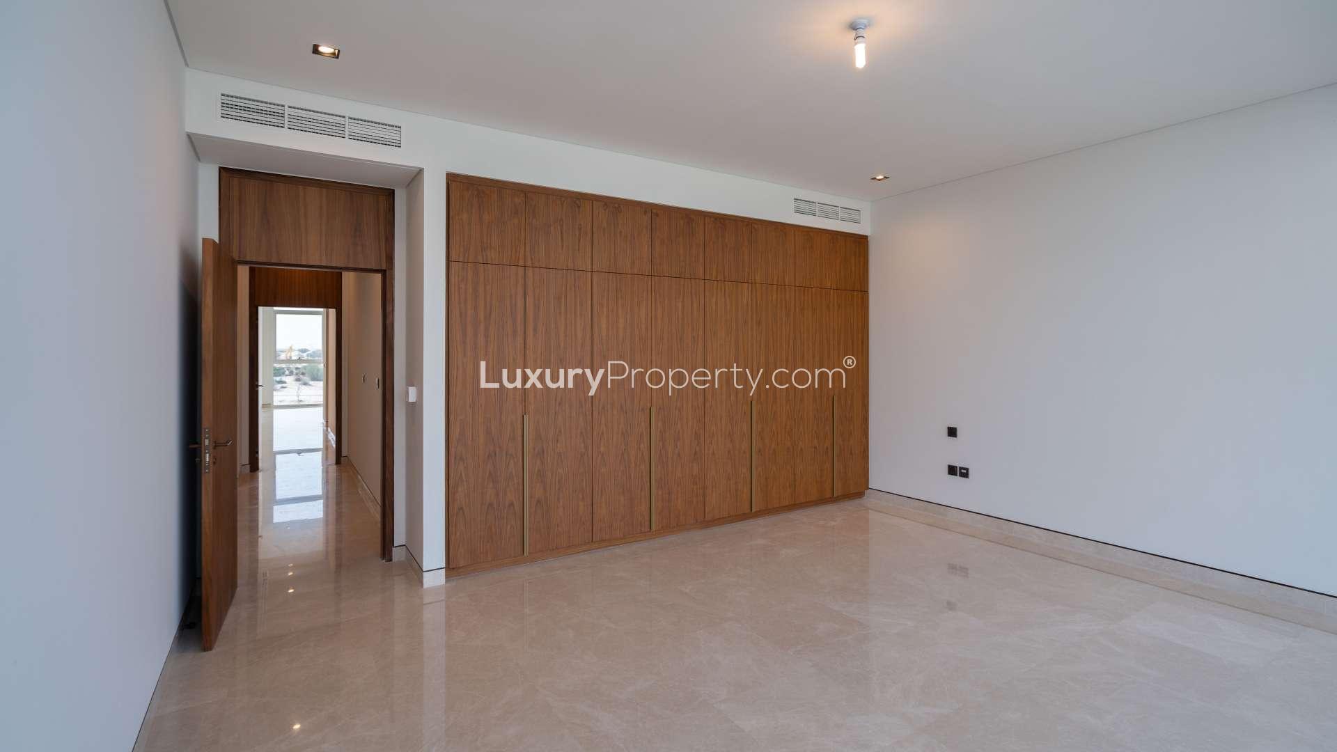 Empty bedroom with wooden built-in wardrobes in Golf Place villa, Dubai Hills Estate