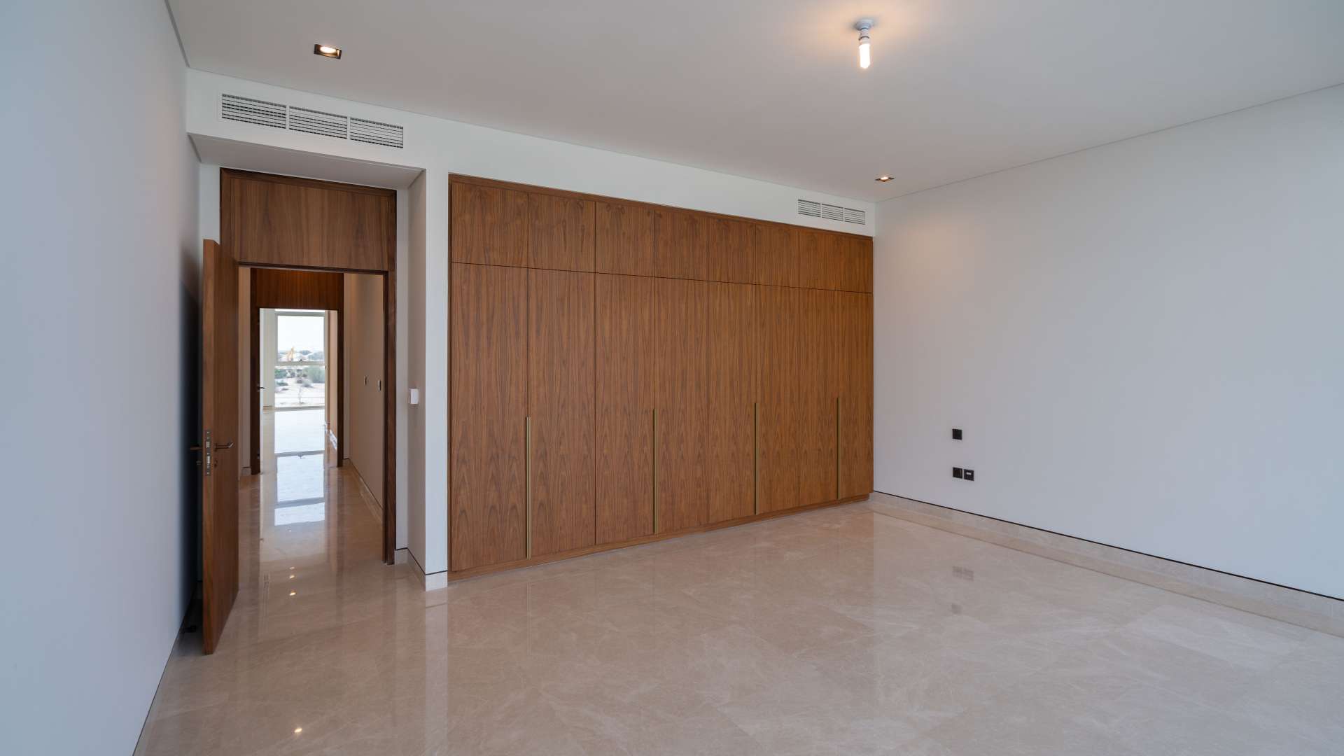 Empty bedroom with wooden built-in wardrobes in Golf Place villa, Dubai Hills Estate